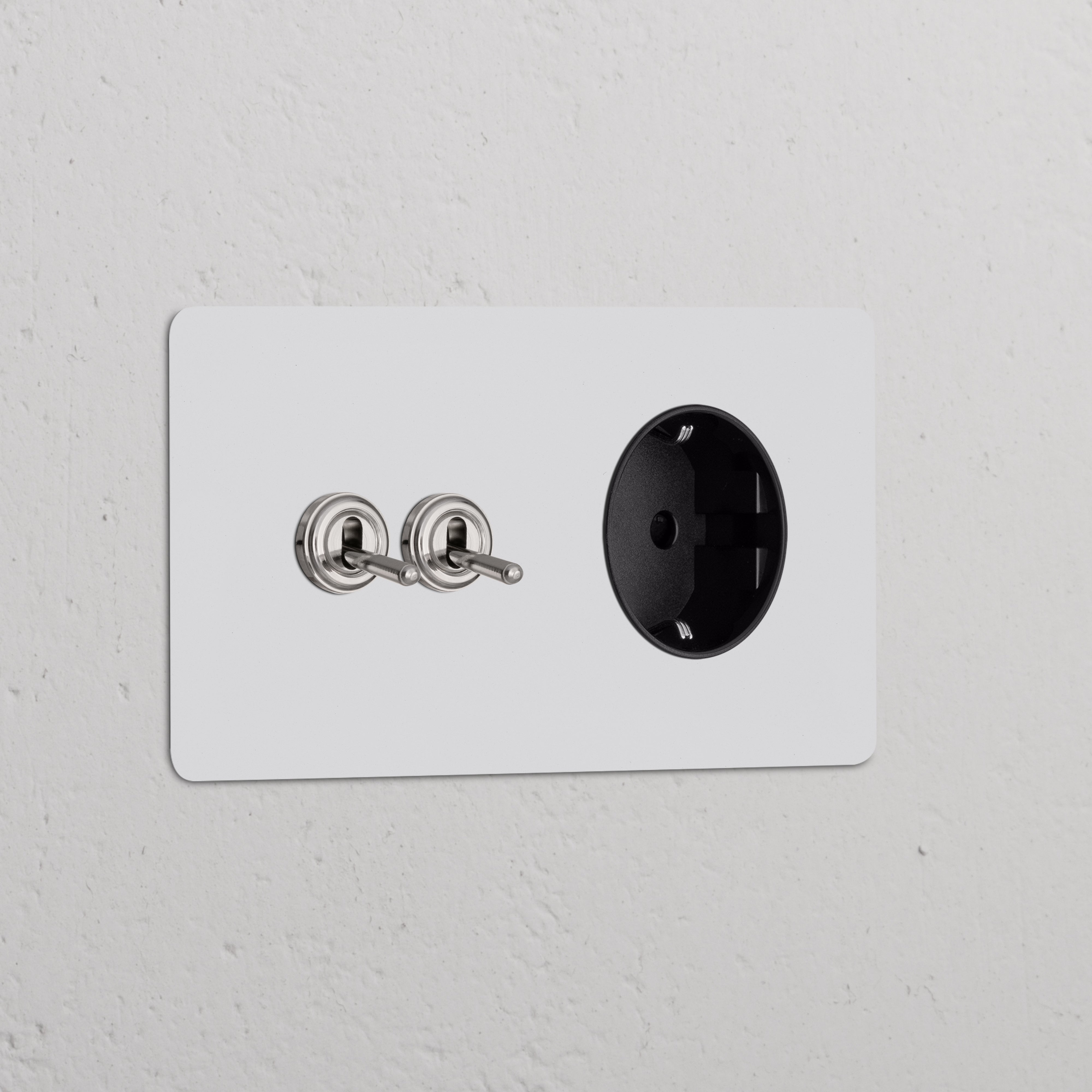 Doppio interruttore a levetta 2x in nichel nero con modulo di alimentazione Schuko Tipo F su piastra a muro verniciabile.