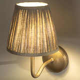 Applique Malvern piccola in Beige Naturale, angolata con dettaglio della paralume plissettato e accesa