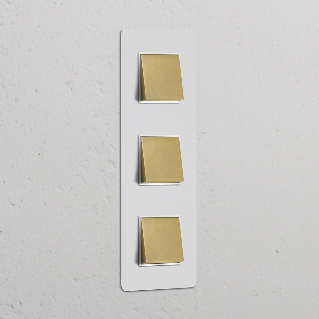 Interruttore a triplo bilanciere verticale, finitura ottone anticato, placca verniciabile bianca; parte della serie 'Interruttori e Dimmer Tripli Verticali'.