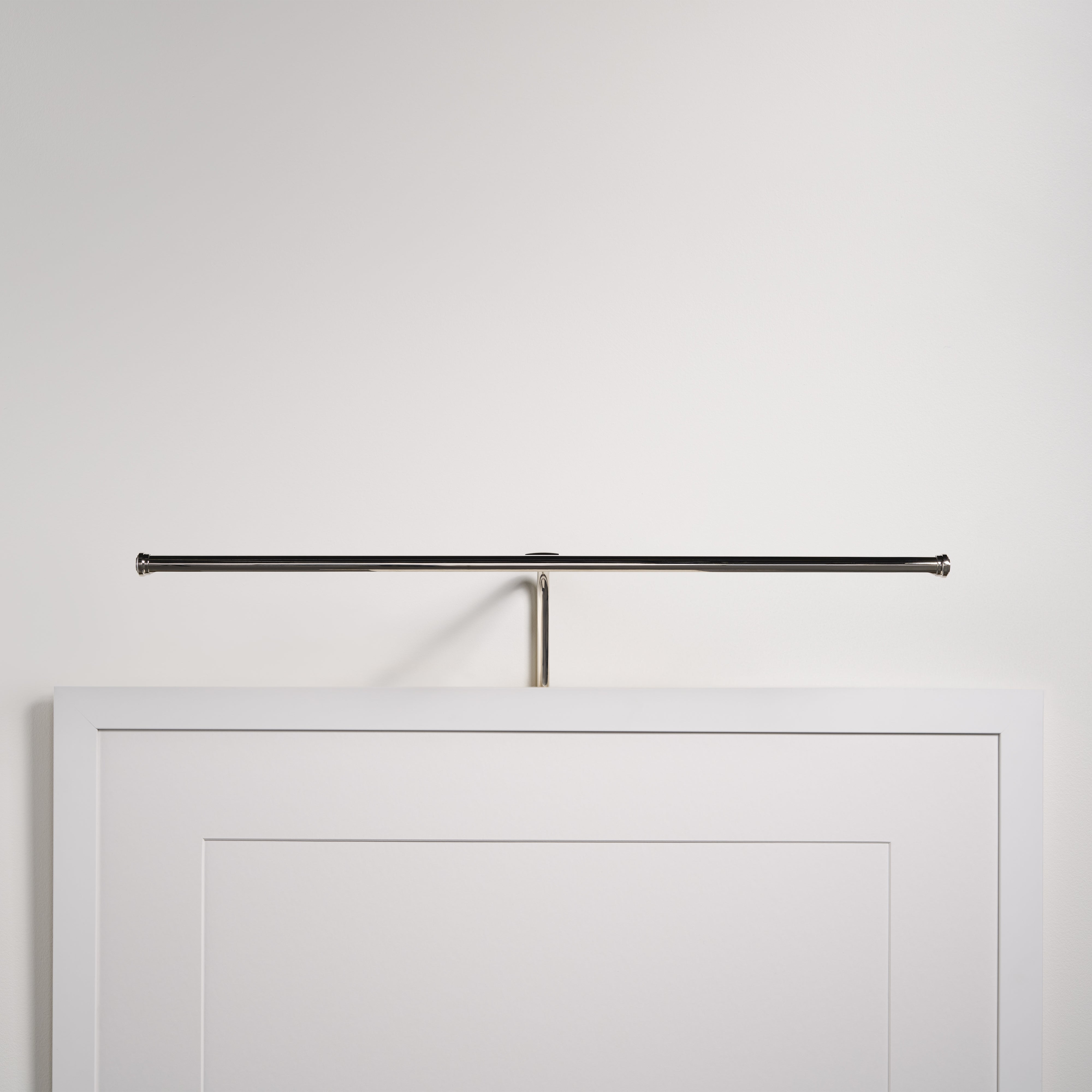 Applique Harrow per Quadri da 580 mm con finitura Nichel Lucido, montata sopra un'opera d'arte con cornice bianca su una parete bianca.