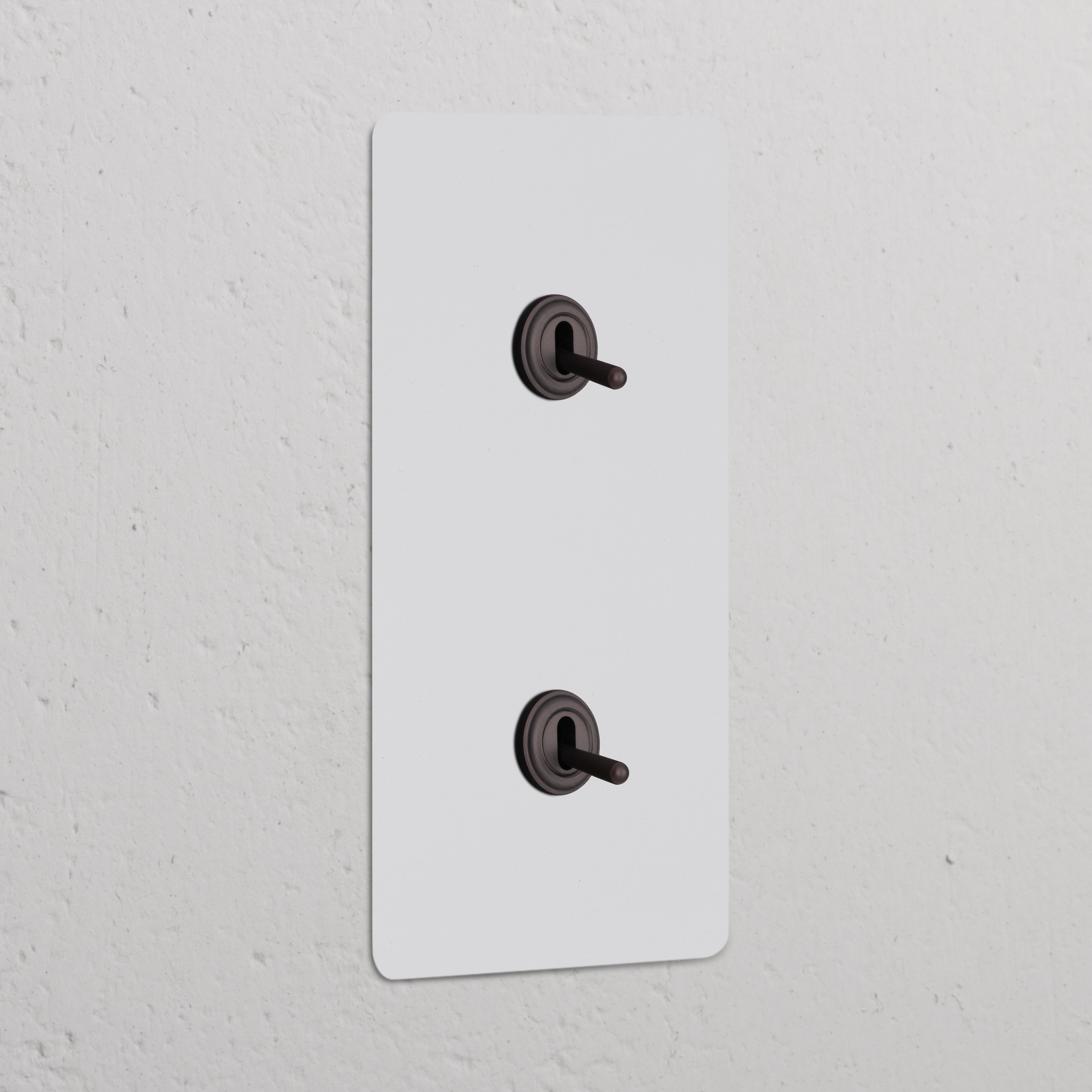 Interruttore a Levetta Doppio Verticale 2x – Pitturabile Bronzo, doppi interruttori verticali su un'elegante placca a muro.
