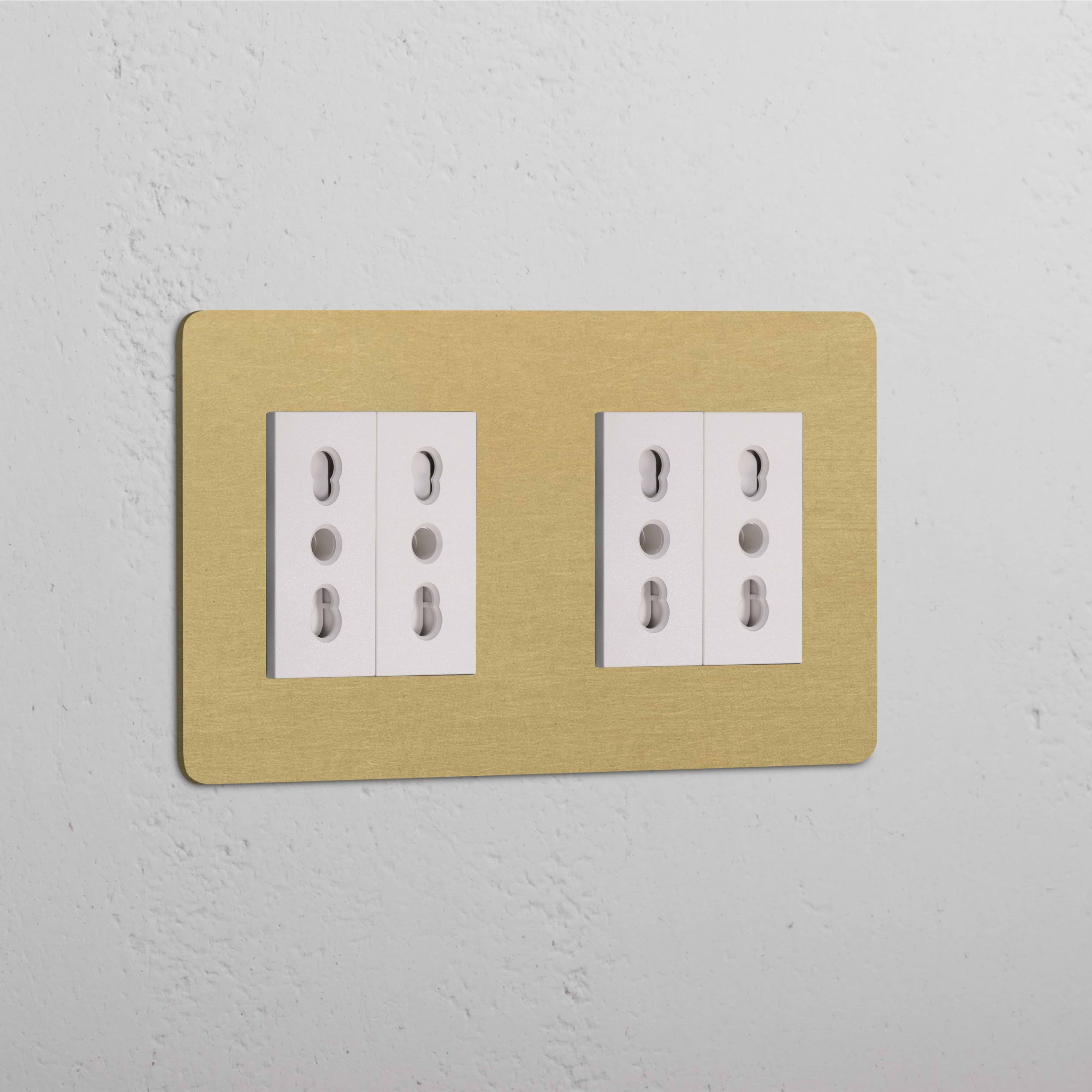 Modulo Doppio 4x Bipasso in ottone anticato e finitura bianca su una piastra beige contro una parete strutturata.