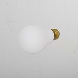 Żarówka LED Mulberry 12 W E27 z mosiężnym gwintem, wykończeniem w kolorze szronionym, na tle teksturowanej, kremowej ściany.