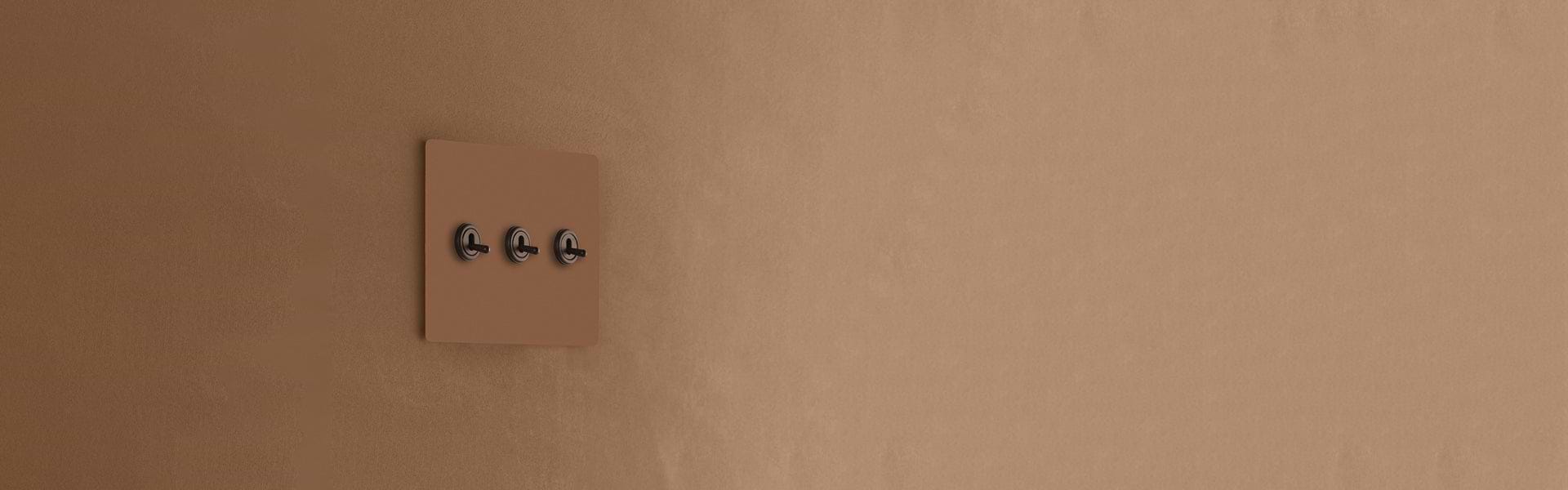 A minimalist brown wall plate with three black switches, seamlessly integrated into a textured brown wall.