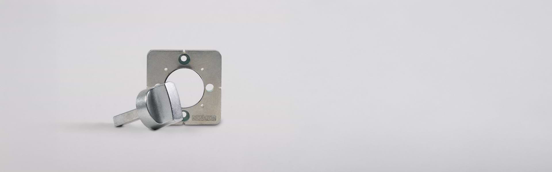 A metal key lies beside a square metal plate with a circular cutout, set against a plain white background.