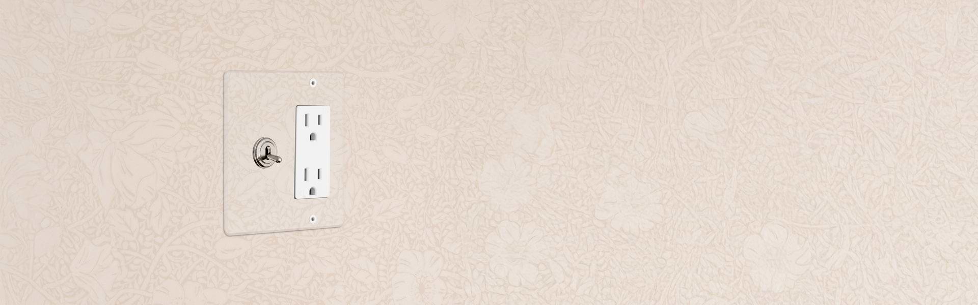 A white electrical outlet and toggle switch installed on a textured light-colored wall.