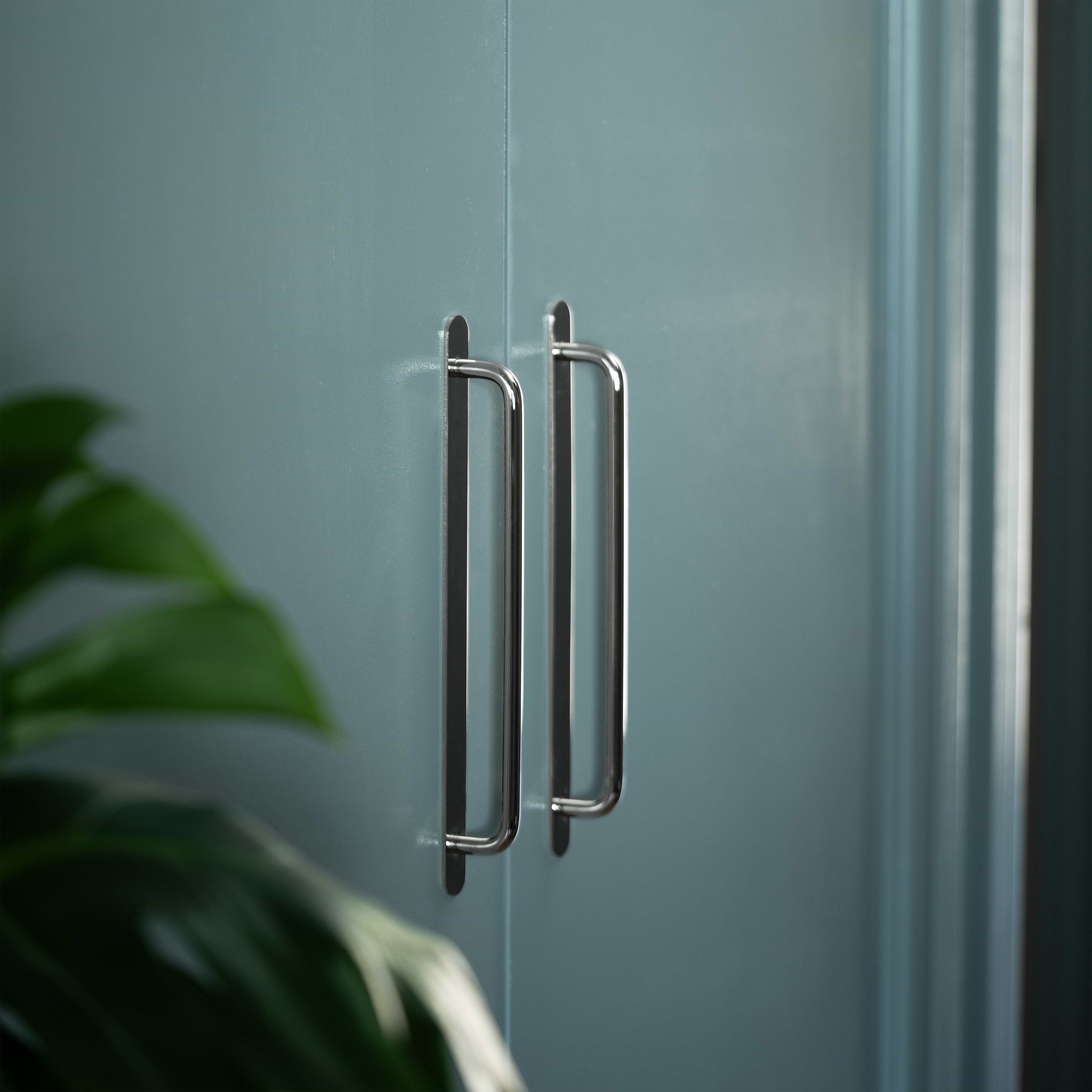 Kilburn Furniture Handle Large in polished nickel installed on a light blue cabinet, plant leaves nearby.