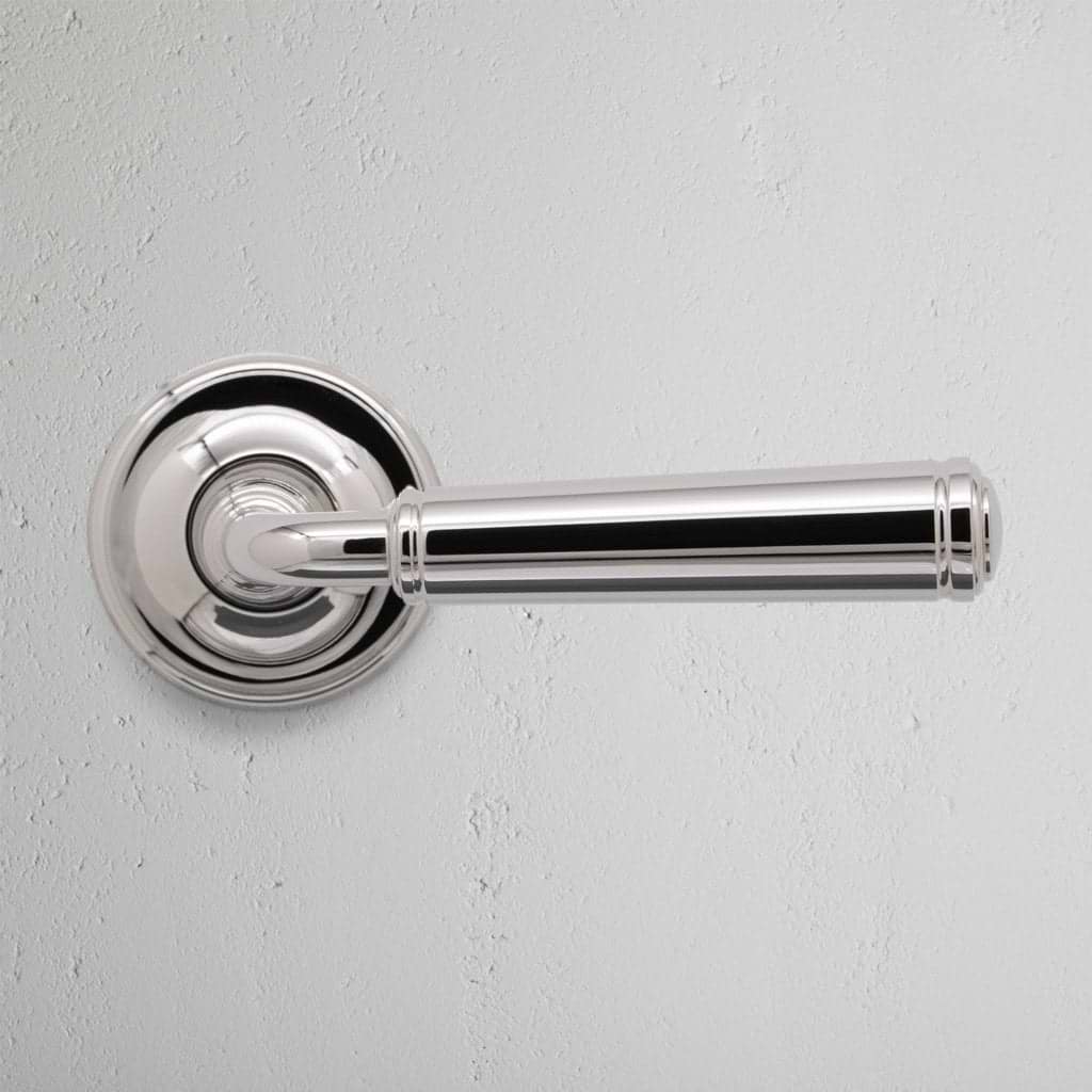 Digby Passage Door Handle Unsprung in polished nickel, shown mounted on a round base plate against a white wall.