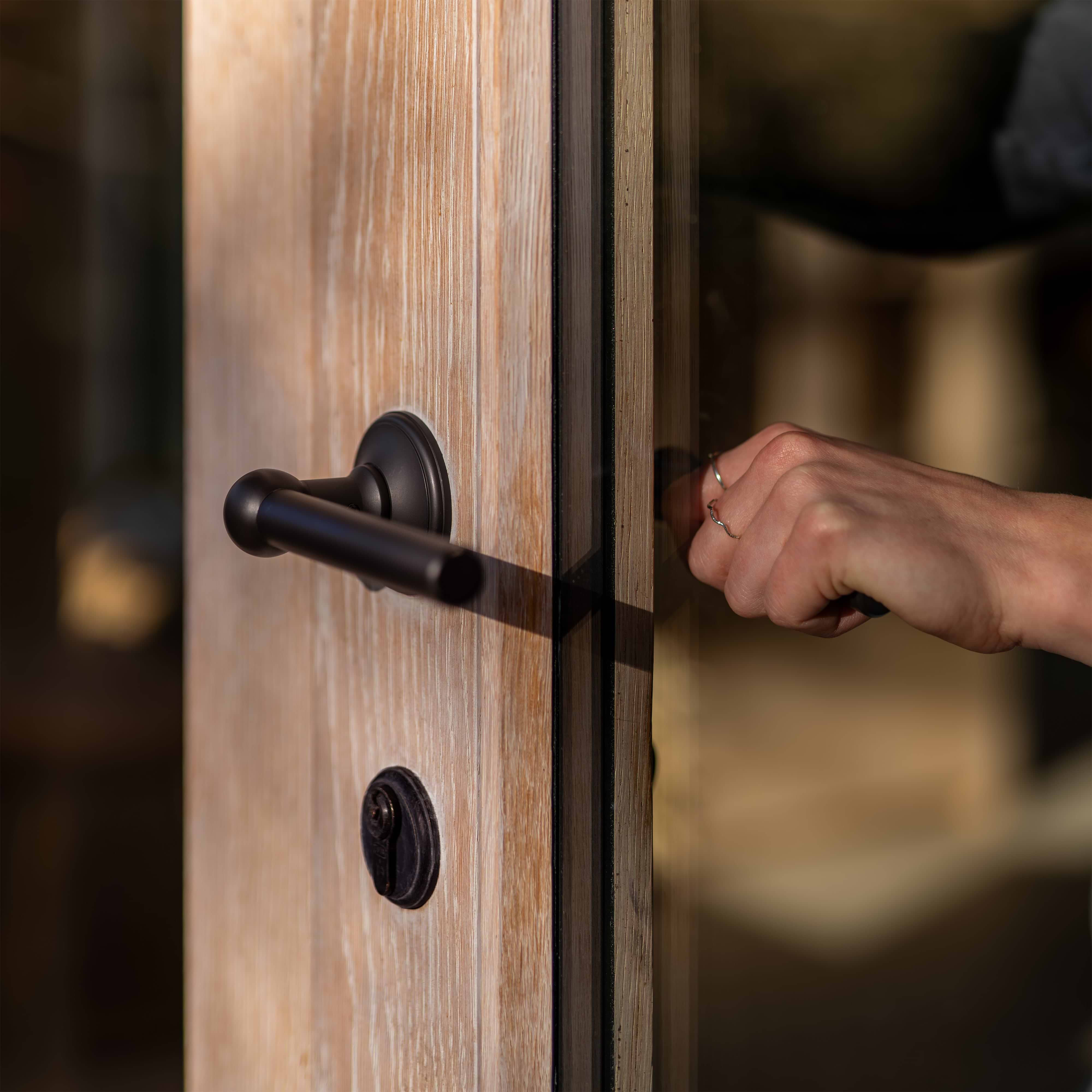 Bronze Canning Key Escutcheon installed on a wooden door, shown around the keyhole area.