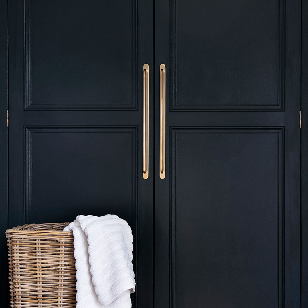 Large Kilburn Furniture Handle in antique brass finish mounted on a dark door.