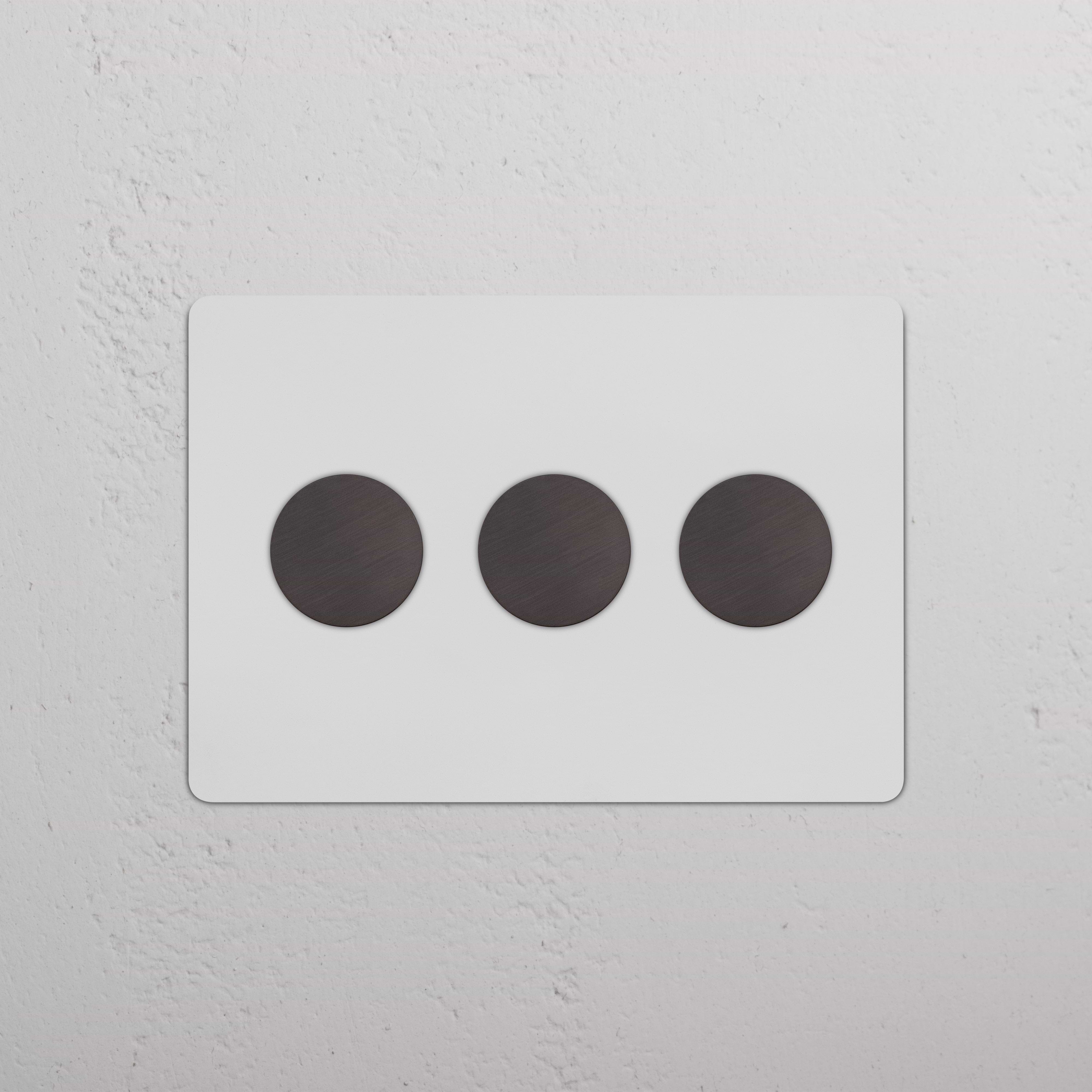Kew 3G Dimmer Switch in paintable bronze finish with three round dimmer knobs, shown on a white wall.