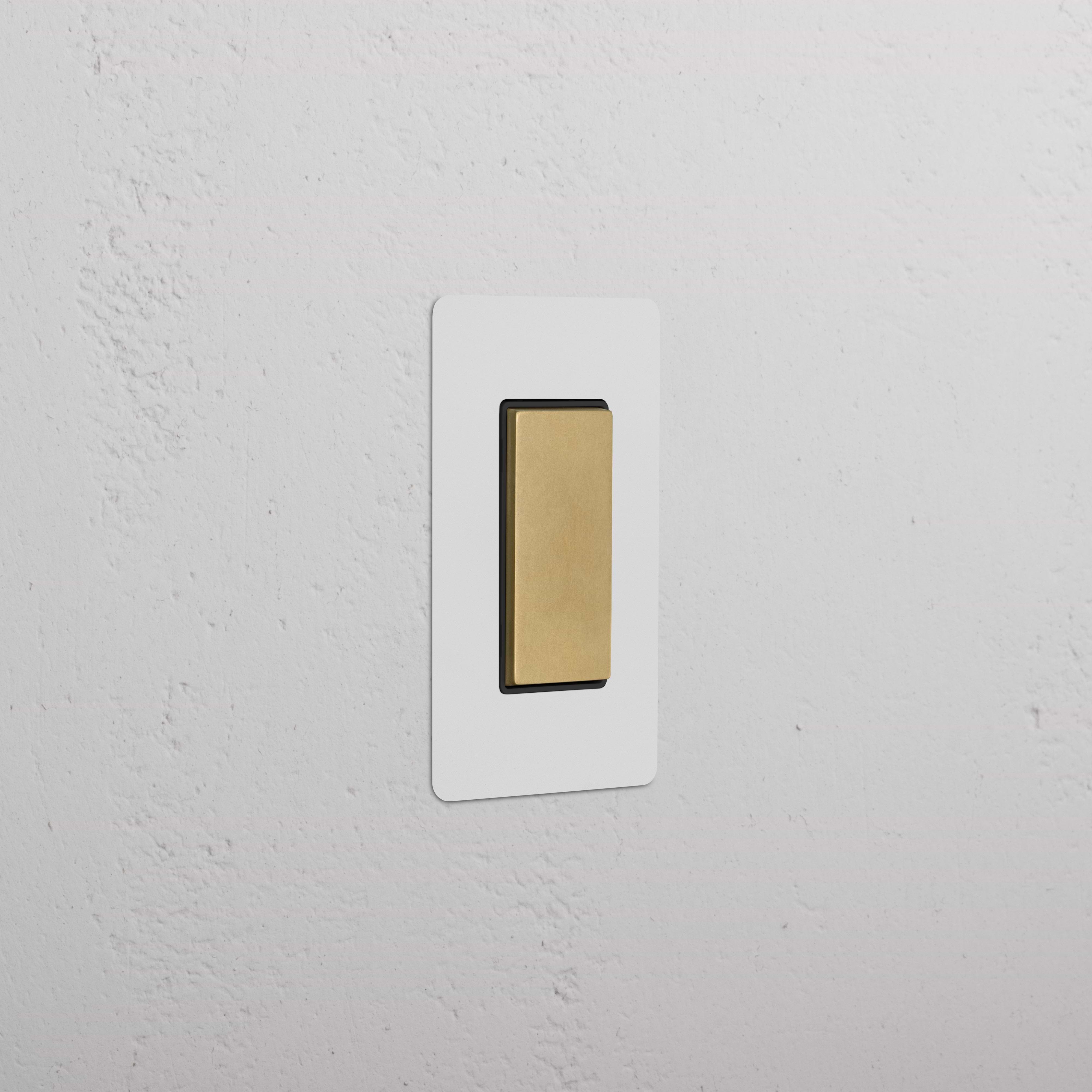 Kew 1G Center Retractive Rocker Switch in paintable antique brass black, shown installed on a white wall.