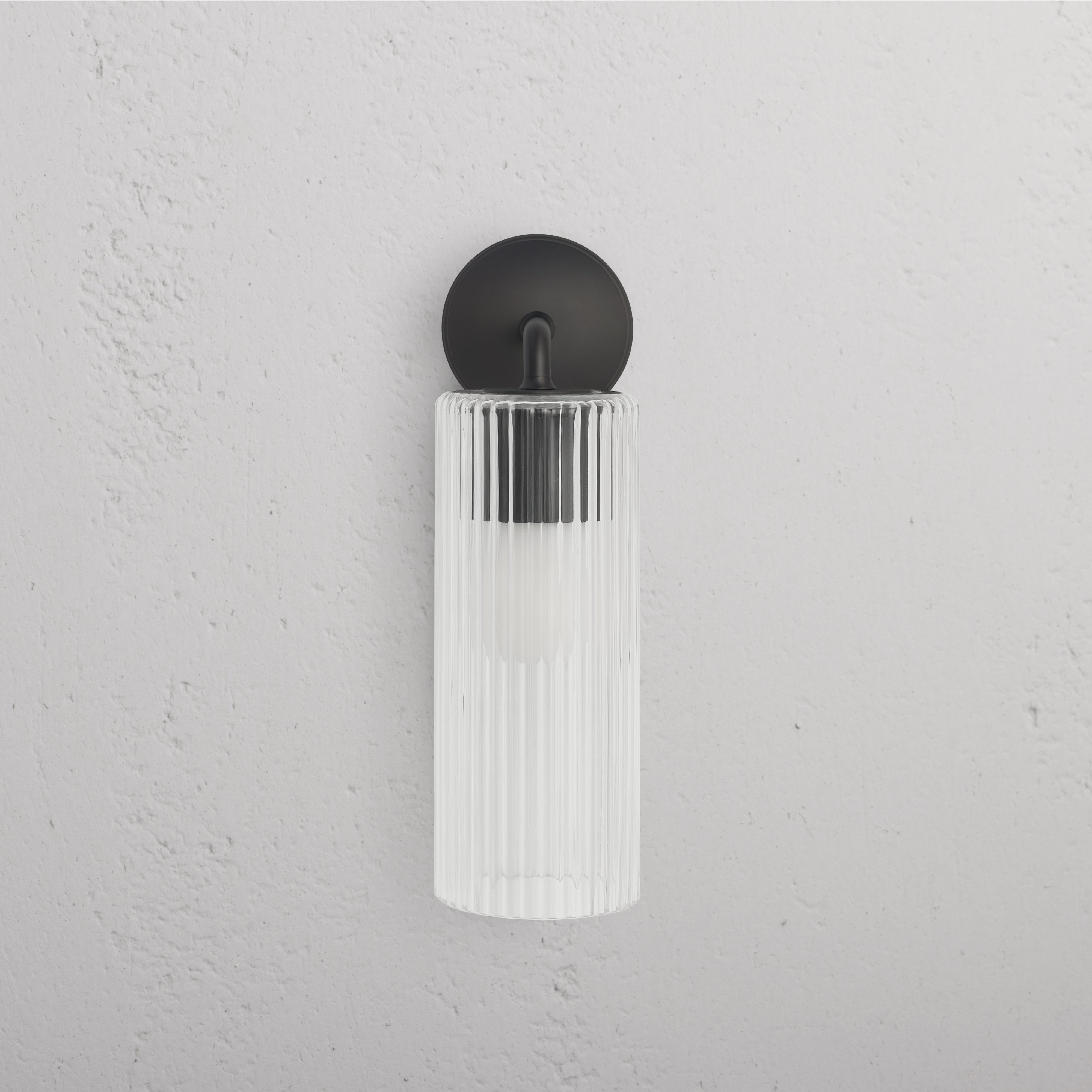 Large Claremont Wall Light in bronze with vertically fluted glass shade, mounted on a white wall.