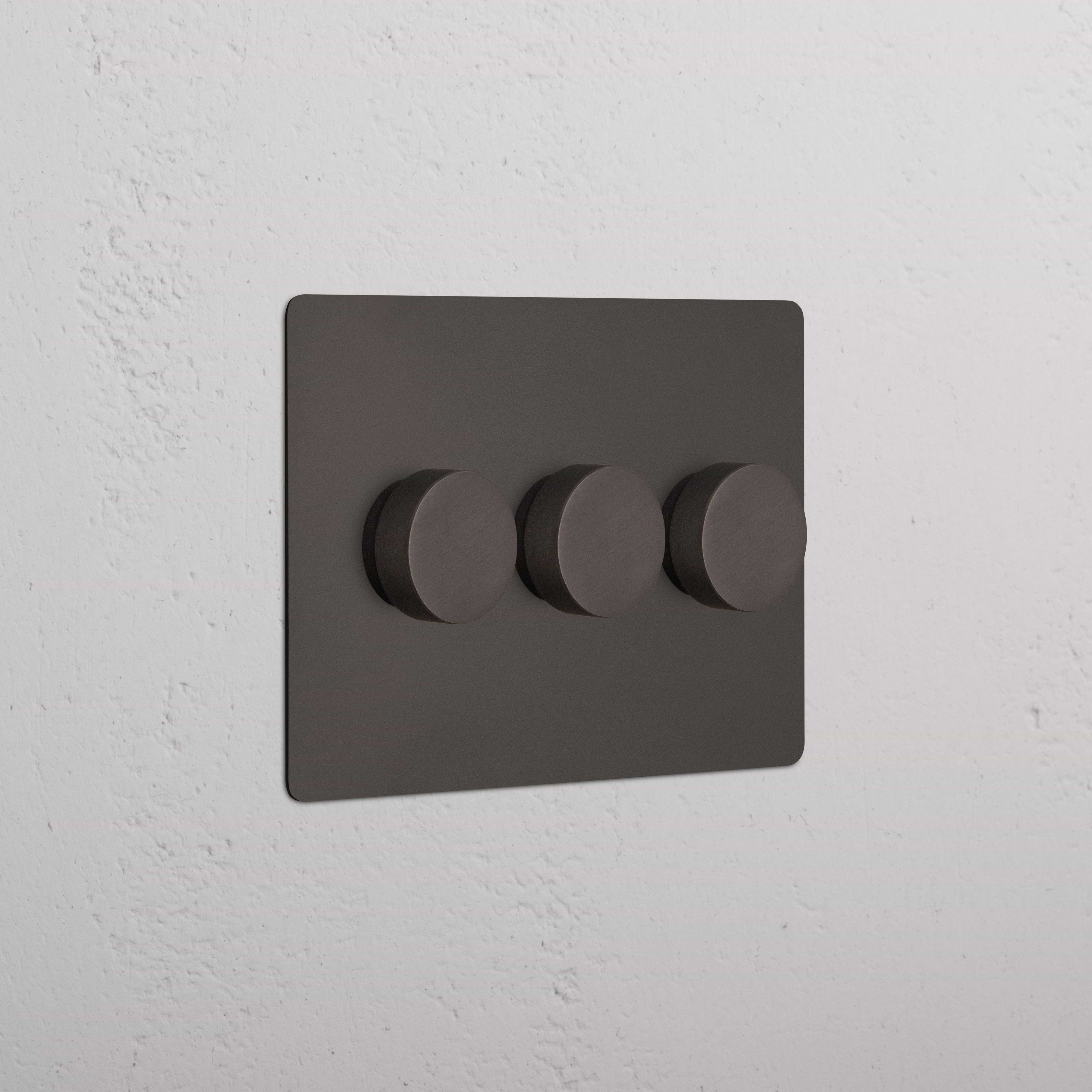 Bronze Kew 3G Dimmer Switch with three round knobs on a textured white wall.