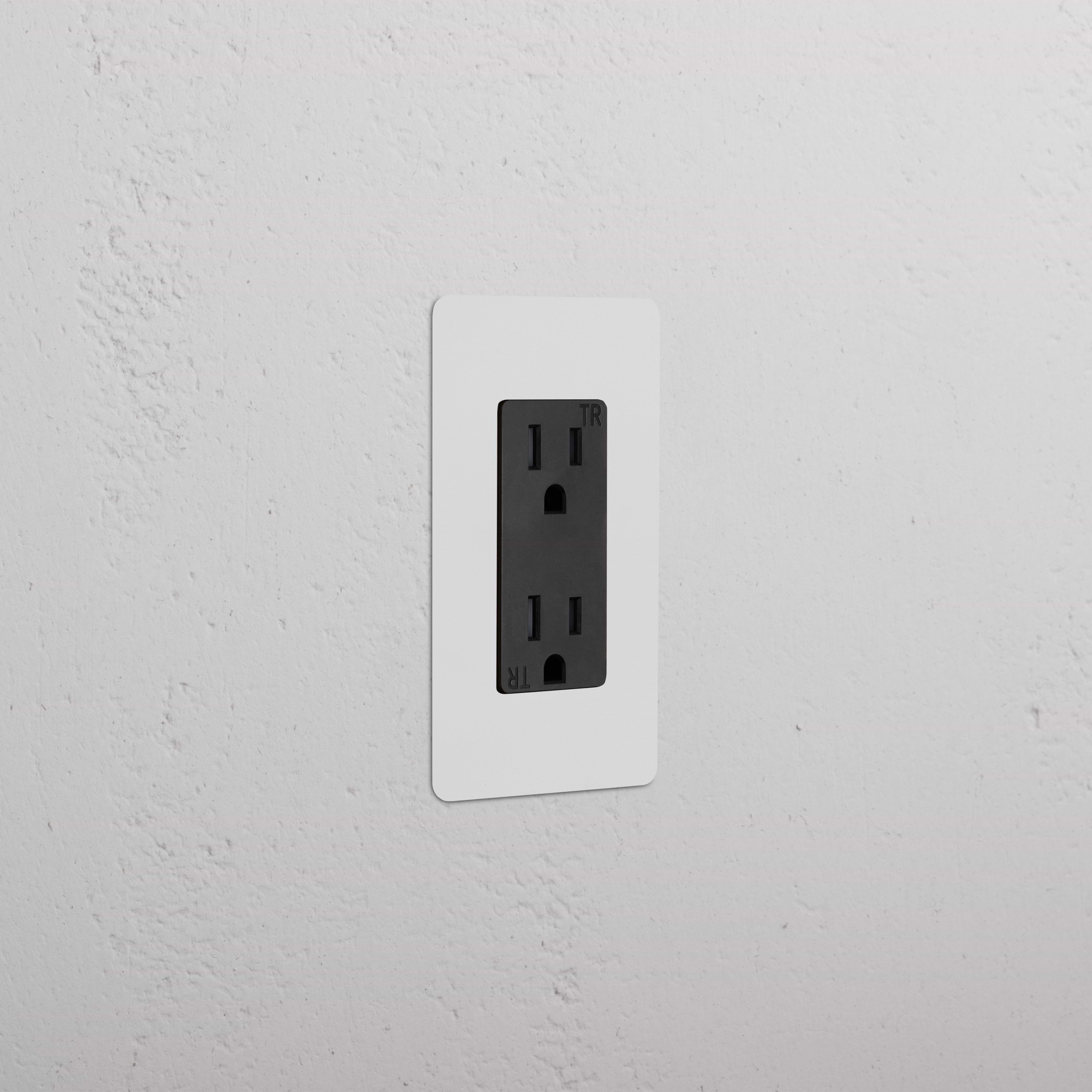Kew 1G 15A Outlet in paintable black with a white faceplate, installed on a textured white wall.