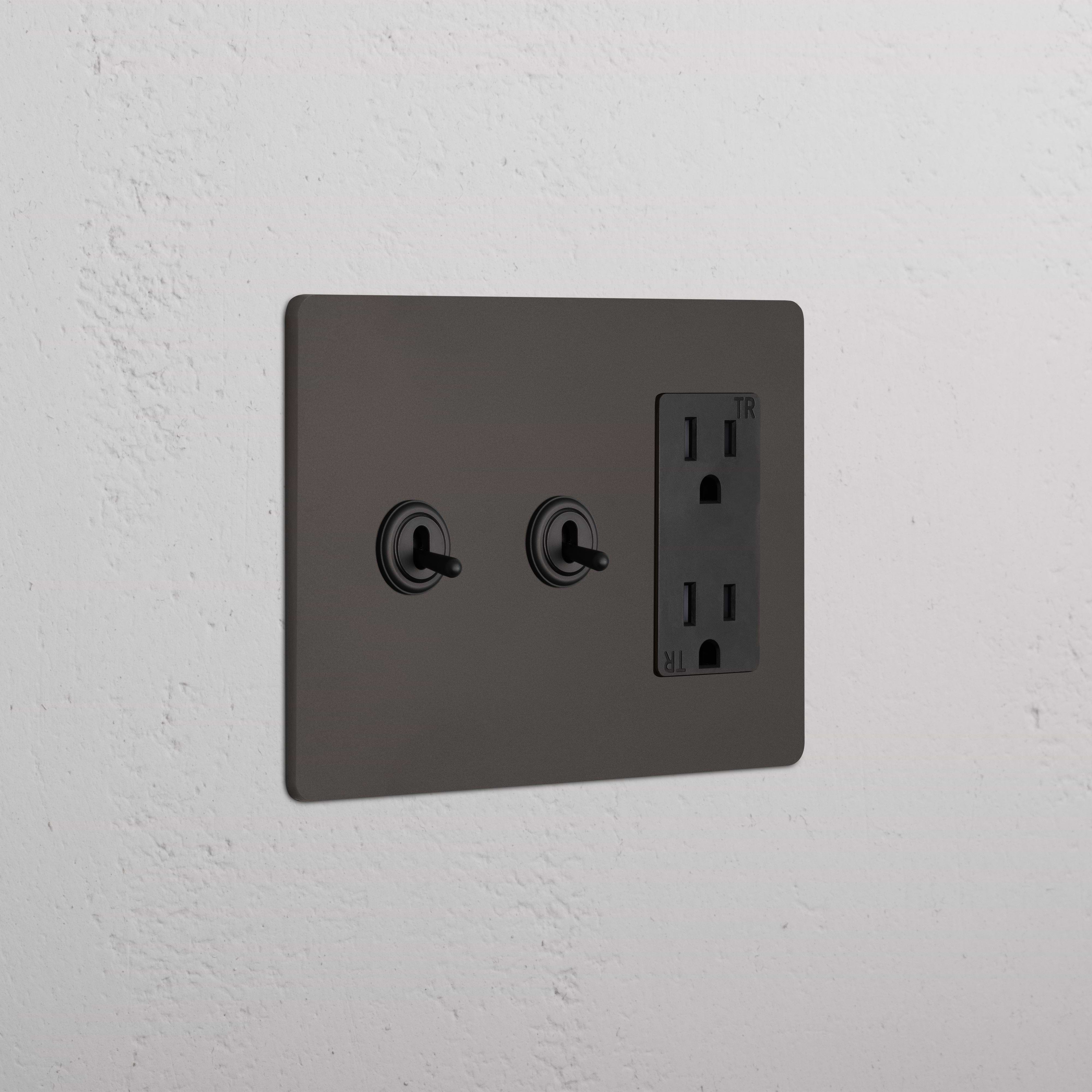 Grove 3G 2x Toggle Switch & Outlet in bronze black with two toggles and one outlet on a matte black plate.