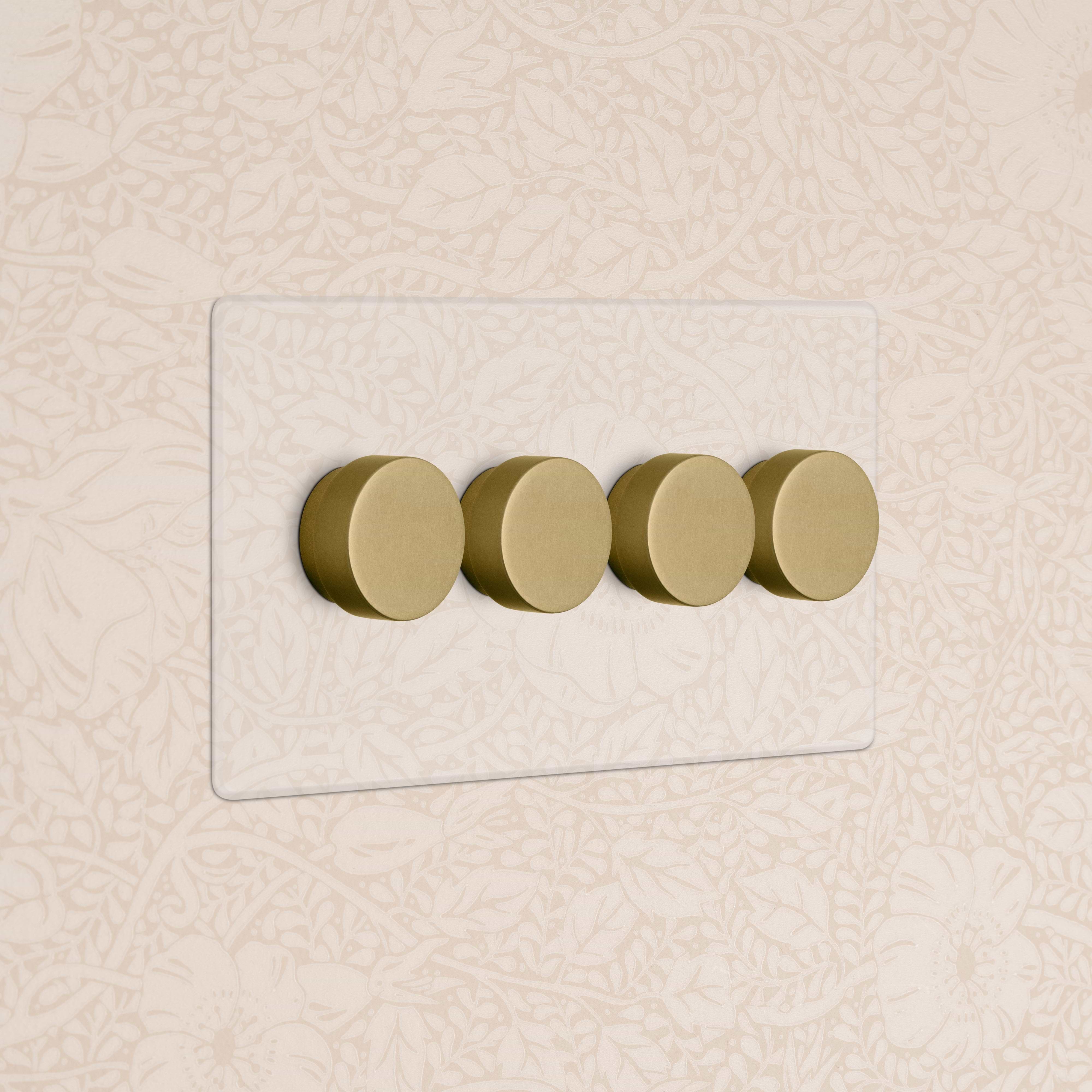 Kew 4G Dimmer Switch with four gold knobs on a clear antique brass plate, mounted on a wall.