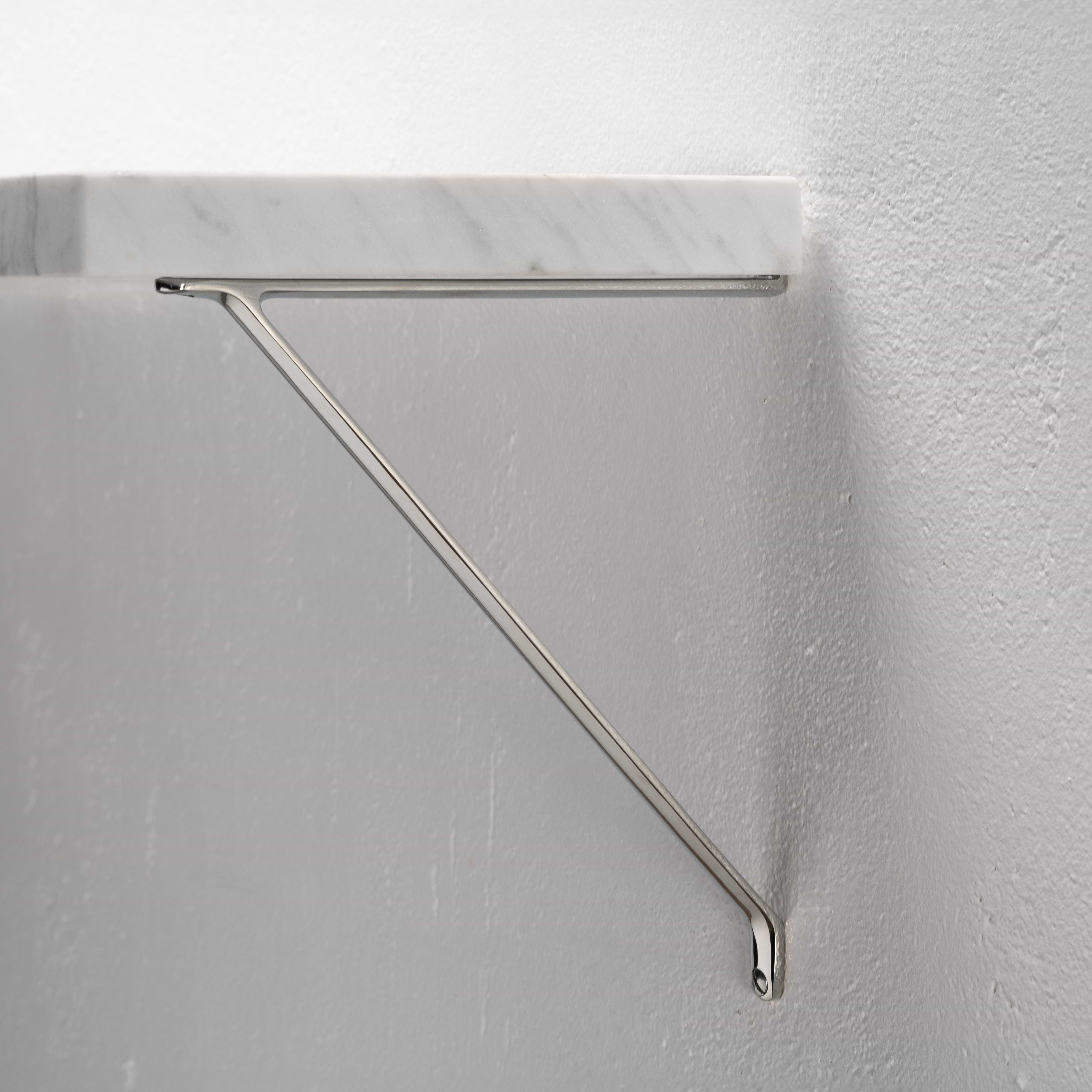 Polished nickel Brixton Shelf Bracket Medium with modern triangular design, mounted to a white wall.