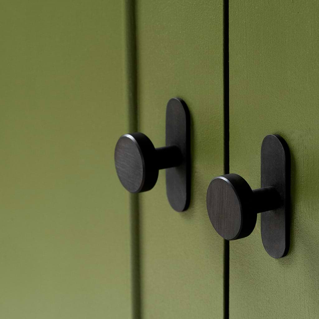 Close-up of two bronze Kilburn Furniture Knobs mounted on olive green cabinet doors.
