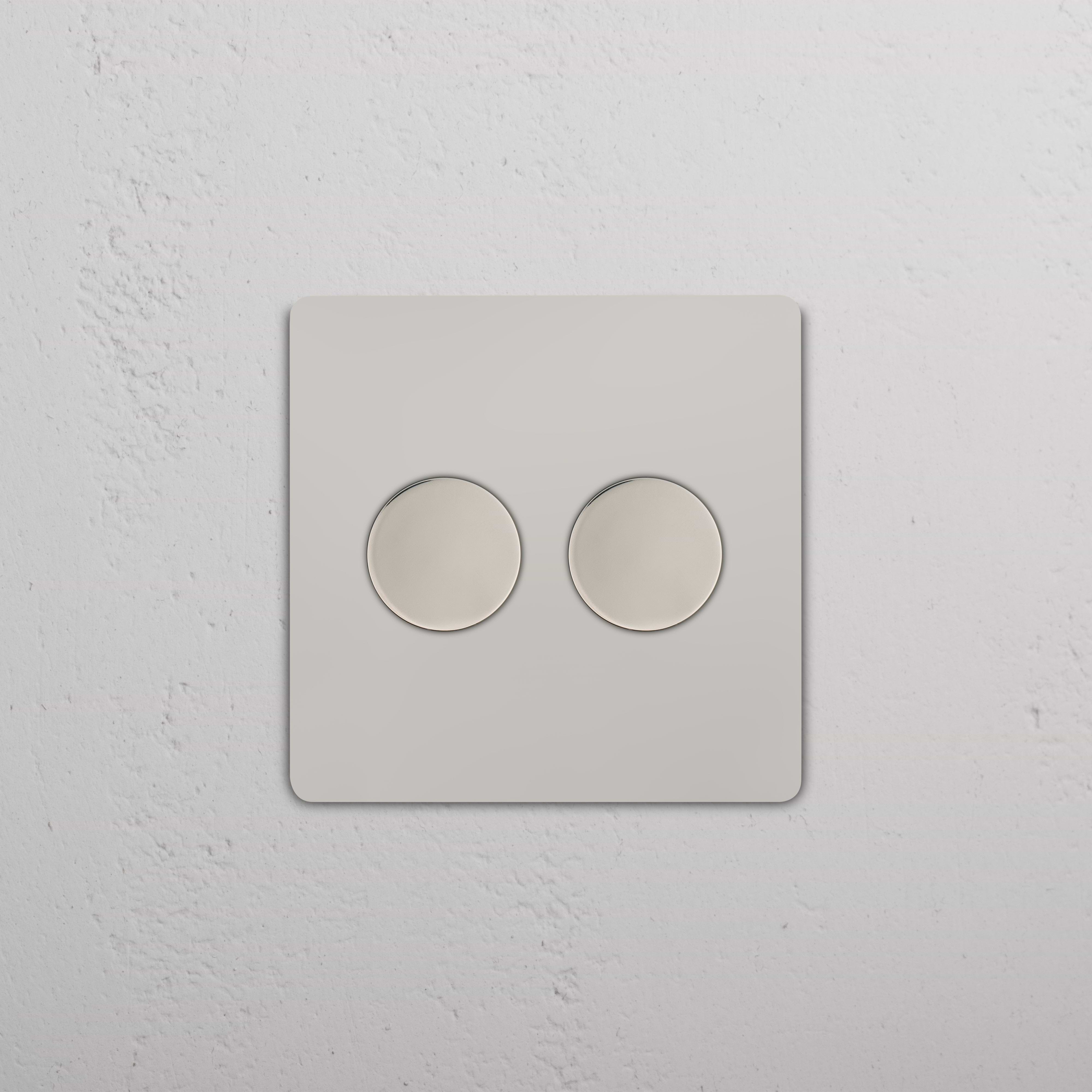 Grove 2G Dimmer Switch in polished nickel with two round control knobs, mounted on a wall.