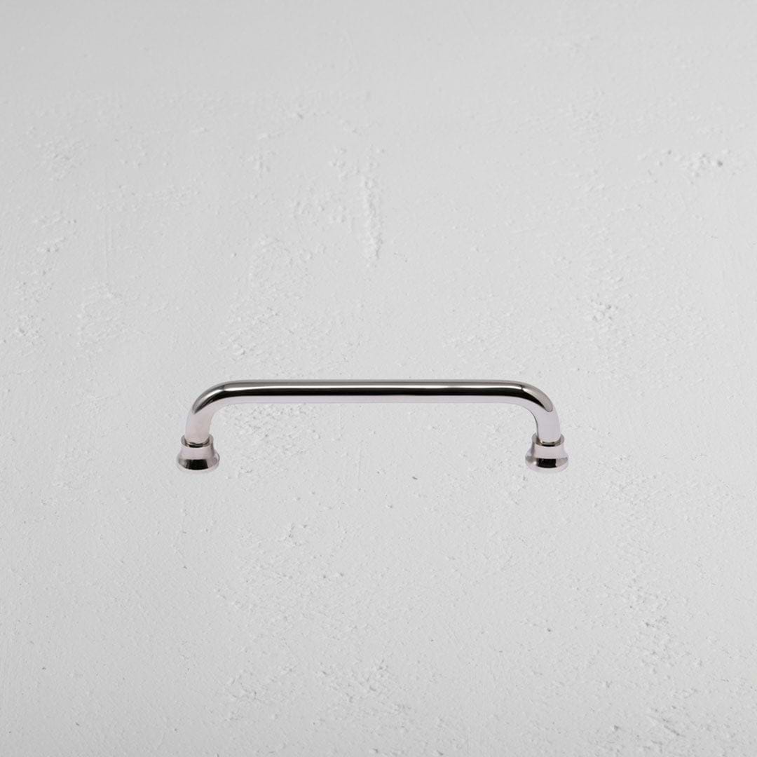 Sycamore Furniture Handle Small in polished nickel, featuring curved edges, mounted on a white surface.