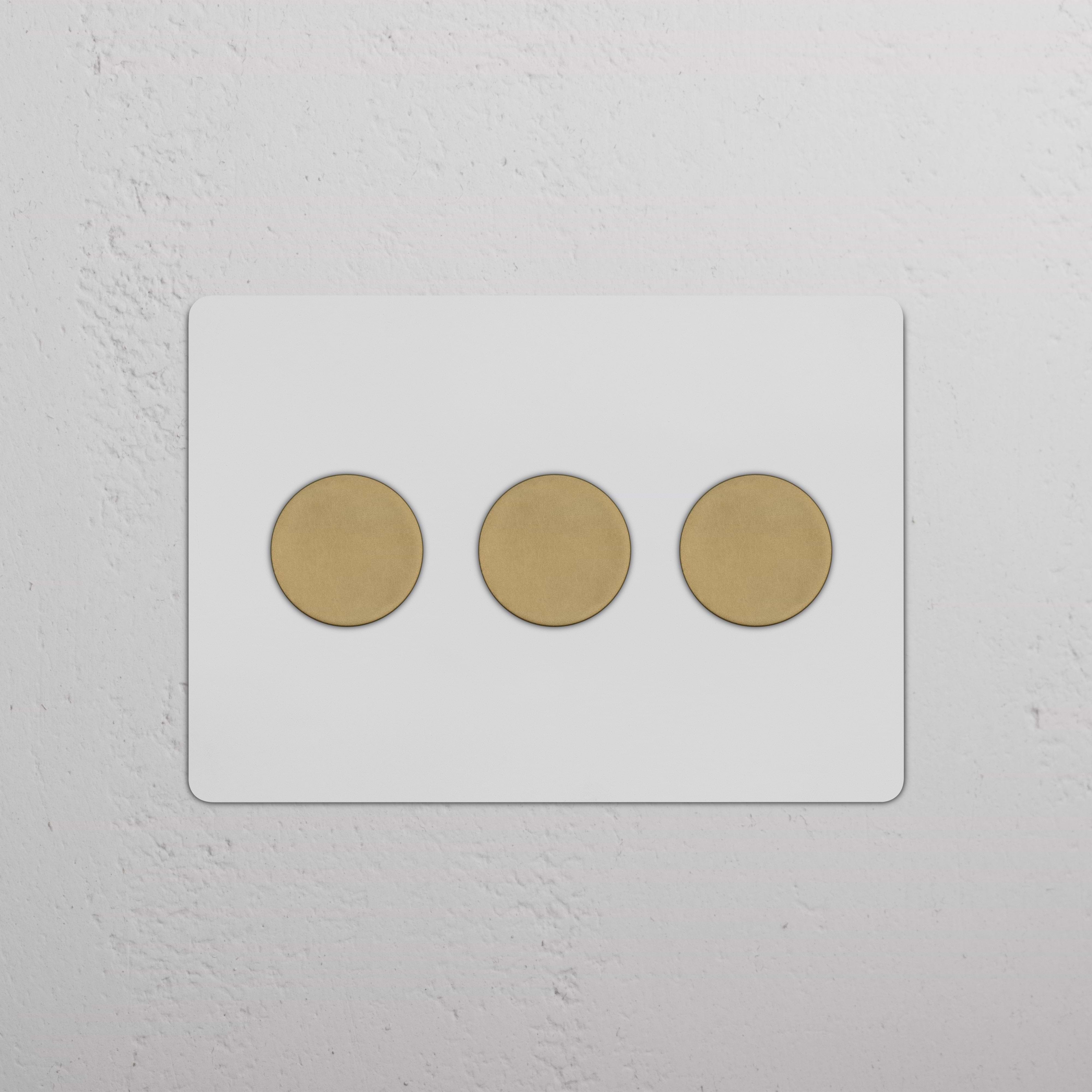 Kew 3G Dimmer Switch in paintable antique brass finish with three round knobs on a white wall.