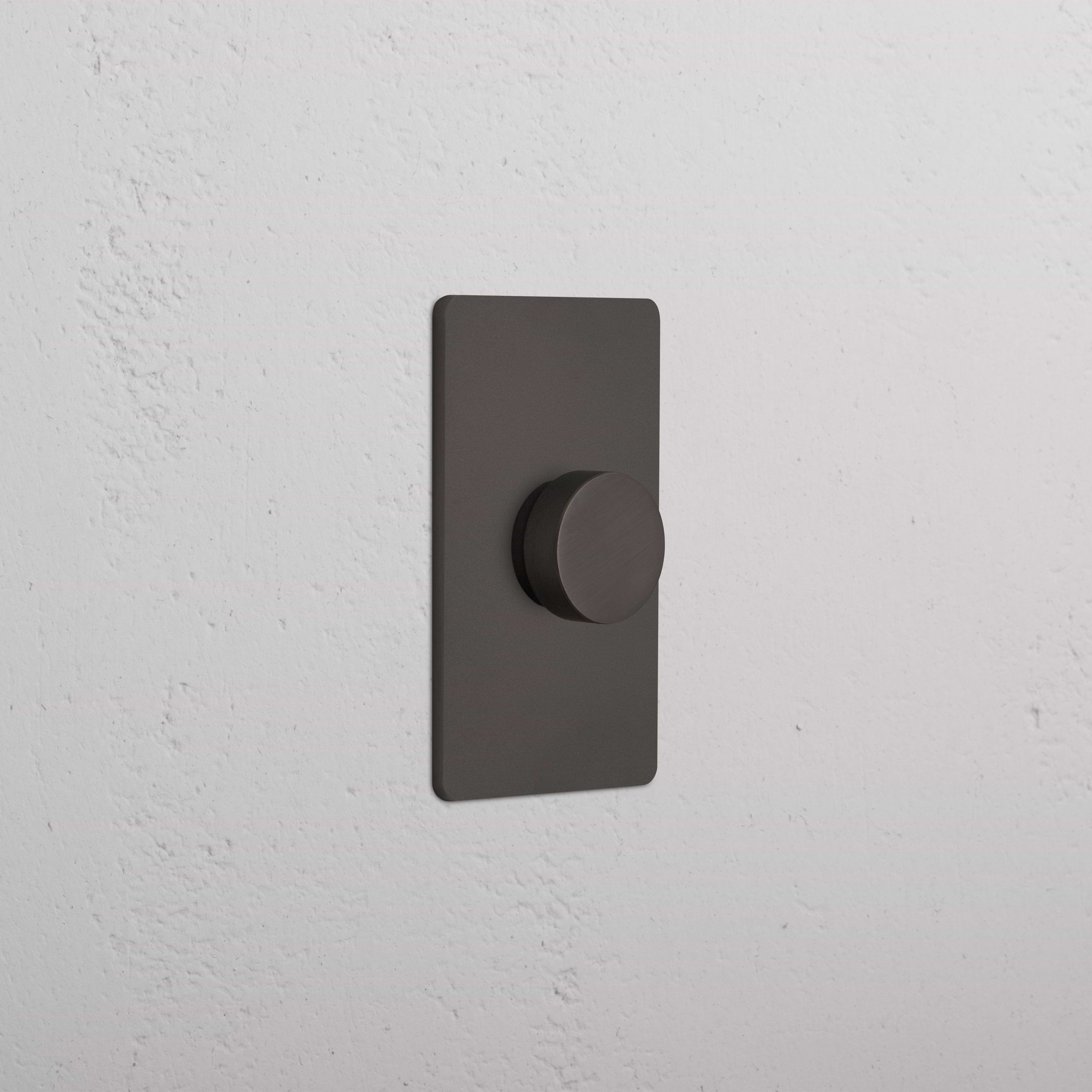 Grove 1G Dimmer Switch in bronze finish with round knob, mounted on a white textured wall.