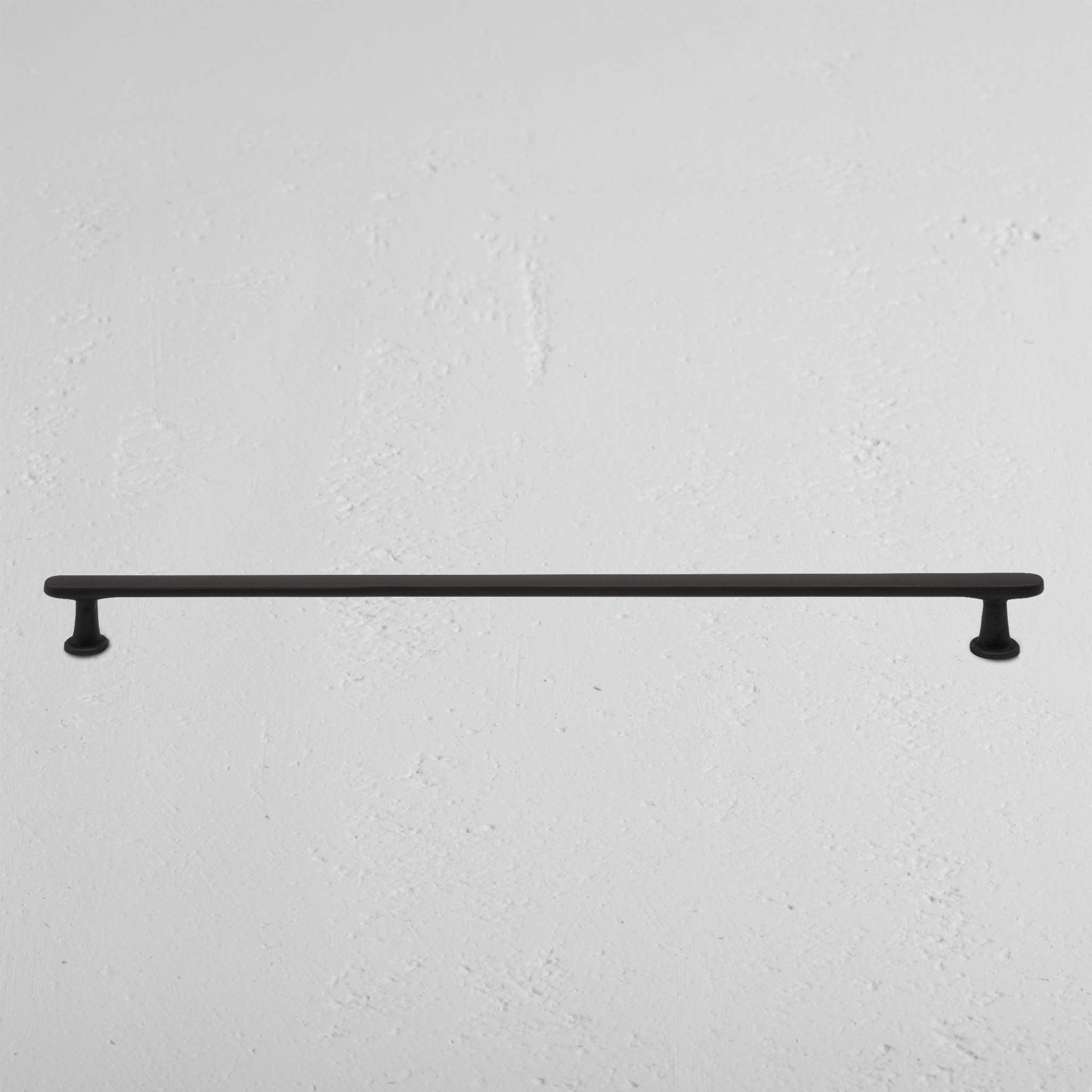 Milliner Furniture Handle Large in bronze finish, mounted horizontally on a textured white wall.