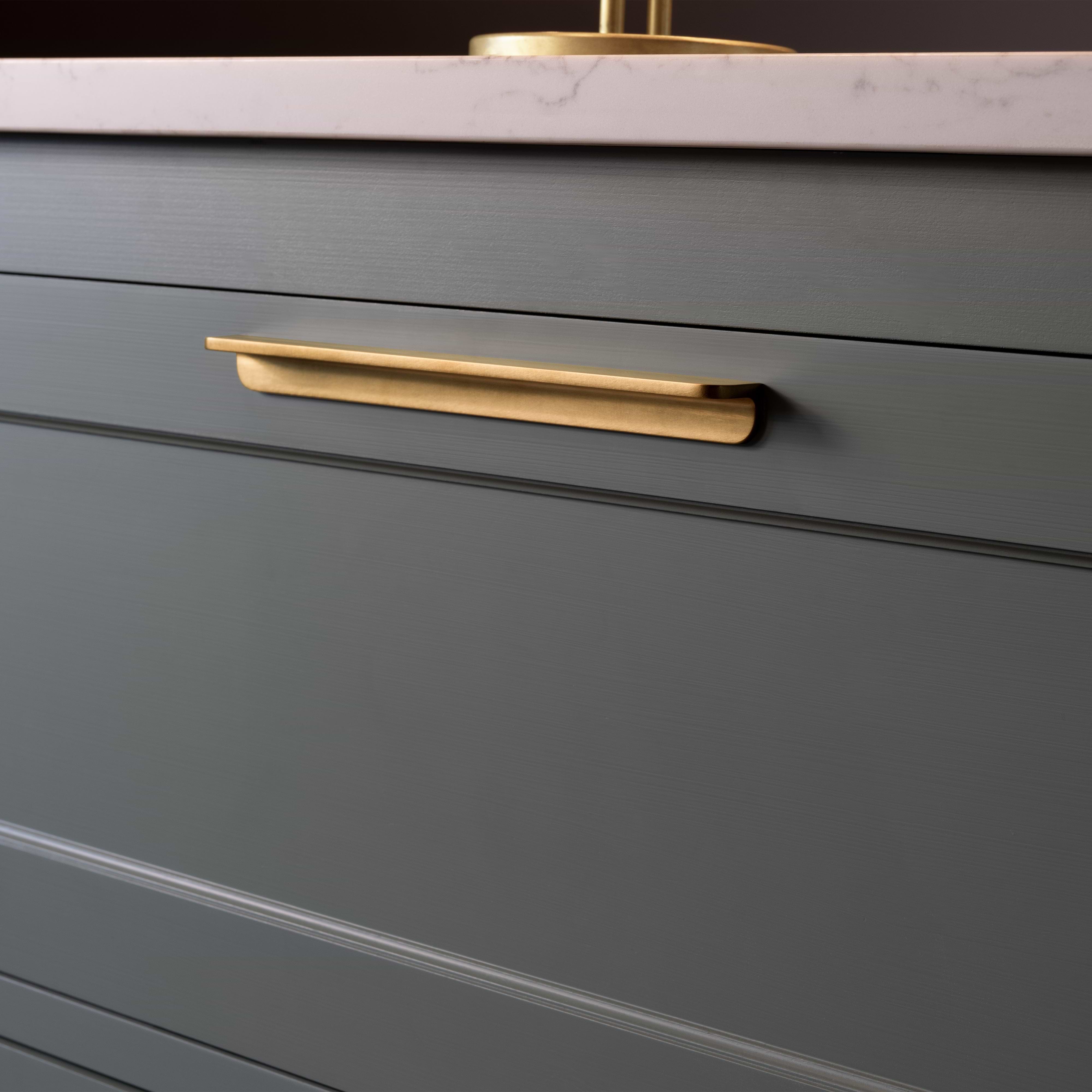 Close-up of an Oxford Furniture Handle Large in antique brass mounted on a green cabinet drawer.