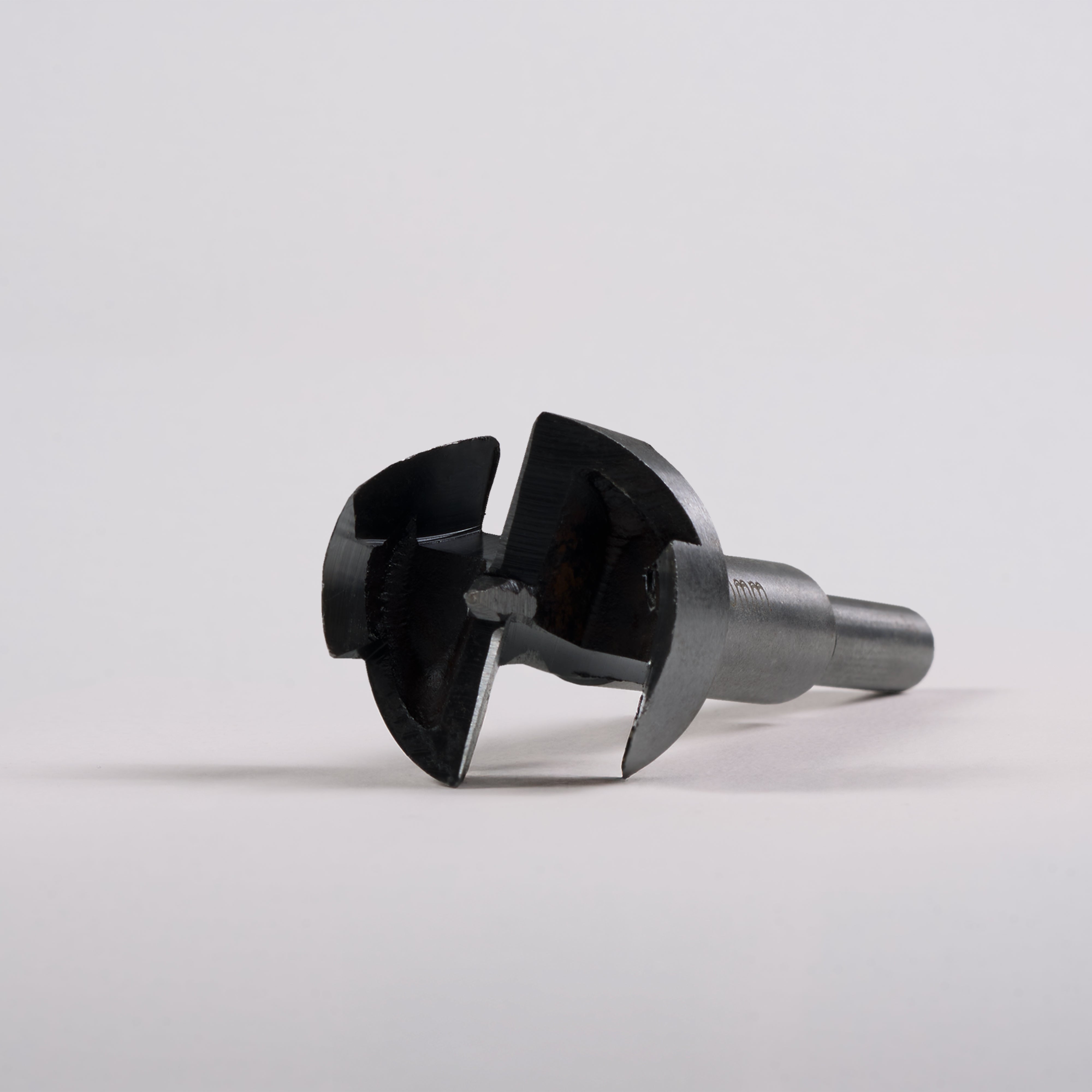 Close-up of a metal Door Handle Installation Drill Bit with sharp, circular cutting edges on a gray surface.