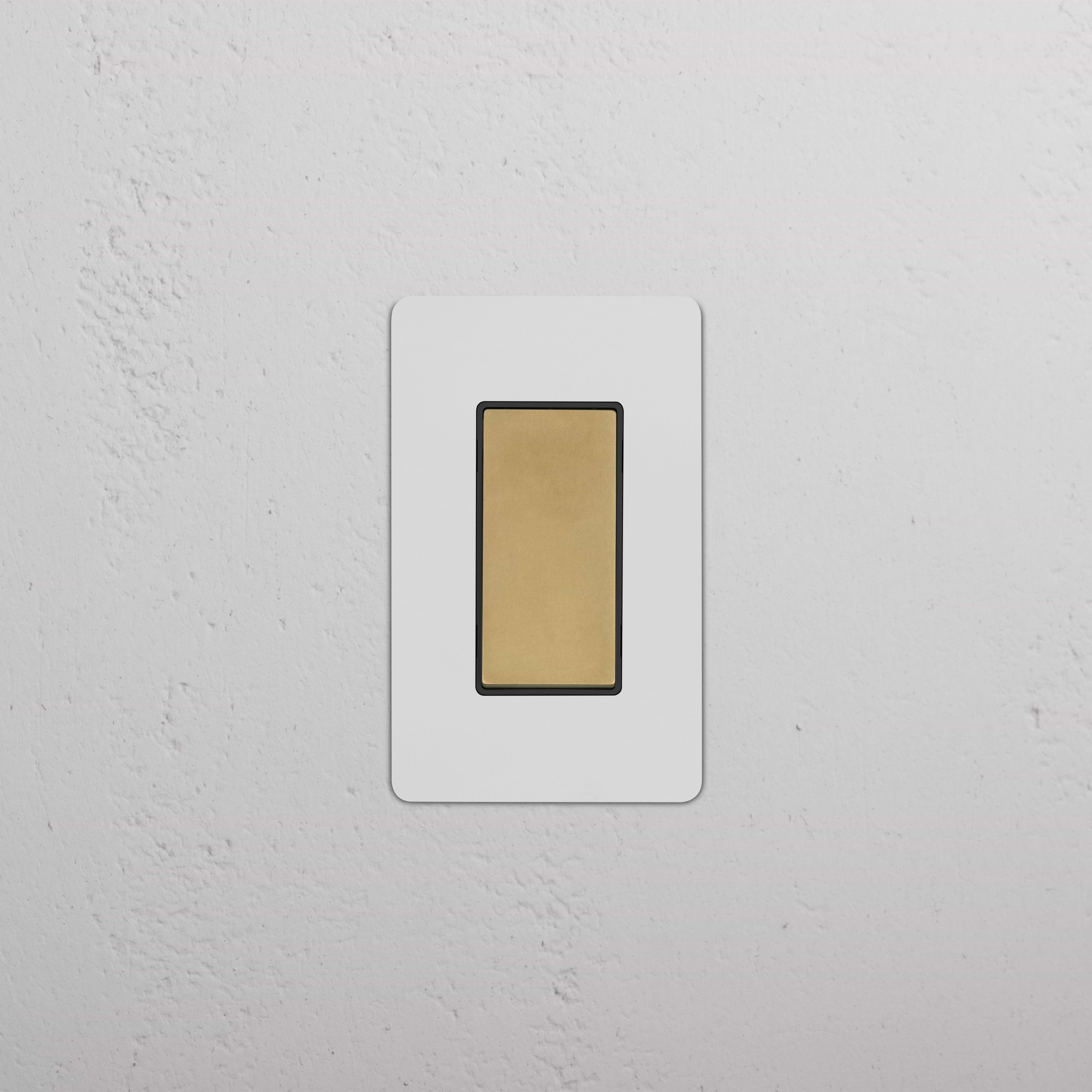 Kew 1G Retractive Rocker Switch in Paintable Antique Brass Black, shown mounted on a white wall.