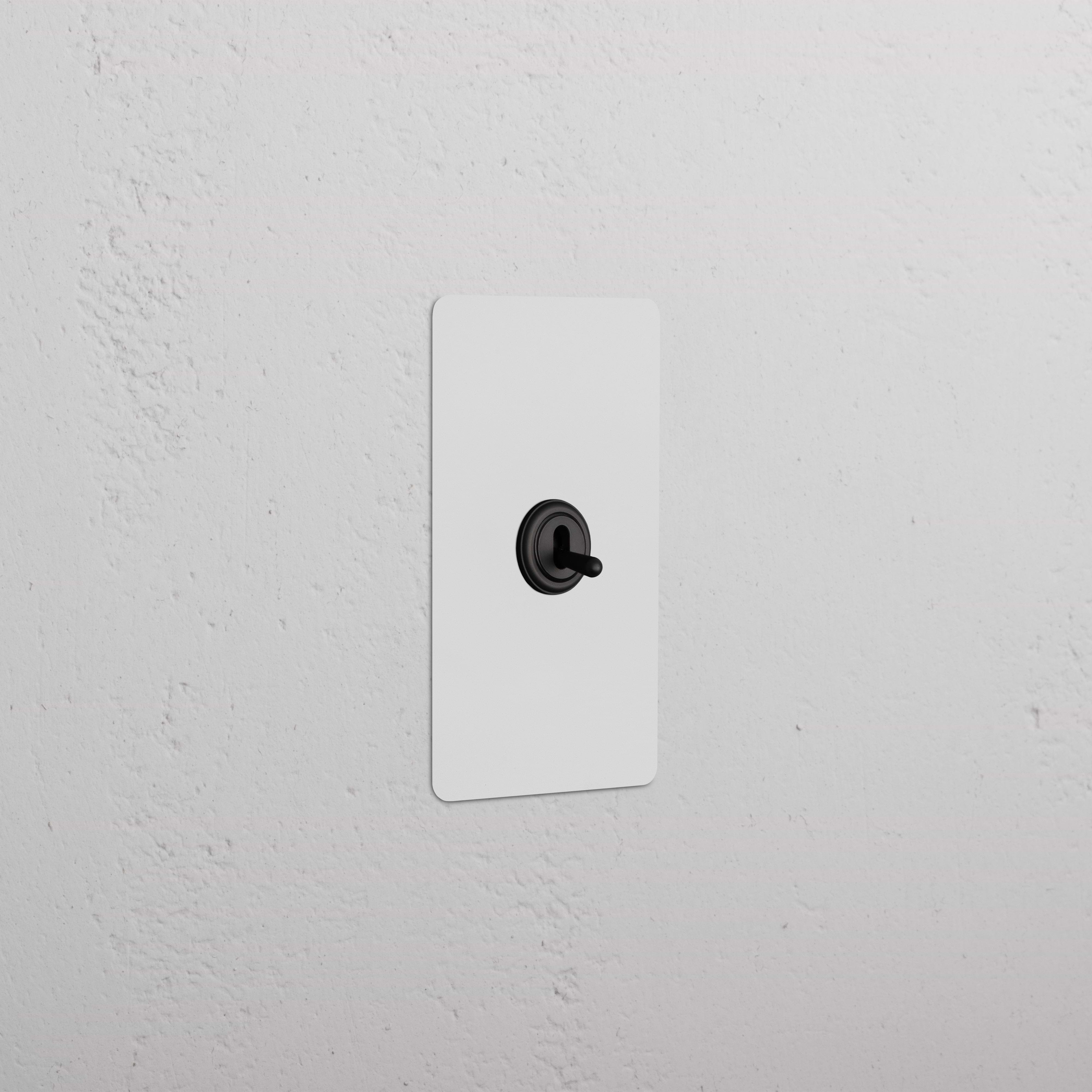 Kew 1G Dimming Retractive Toggle Switch in paintable bronze finish, shown mounted on a white wall plate.