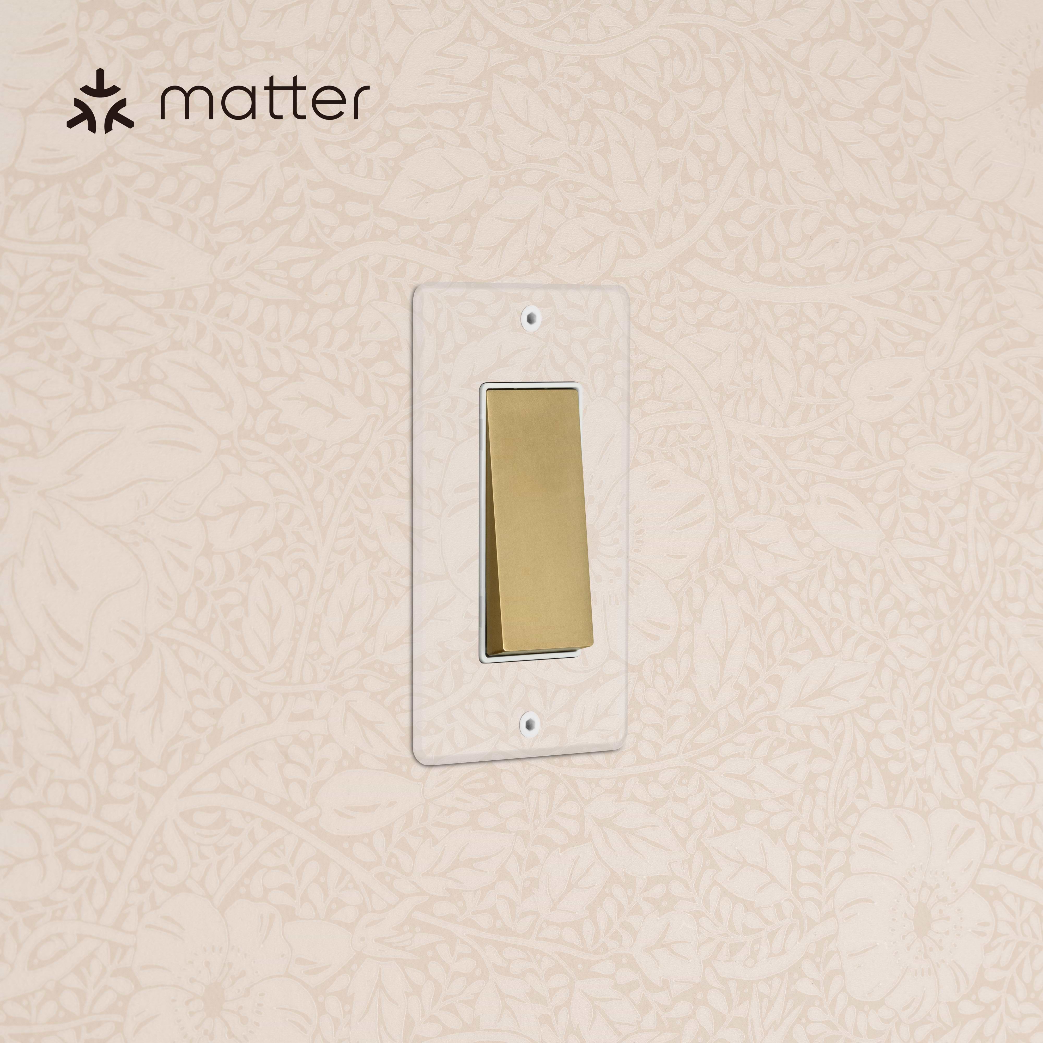 Kew 1G Smart Retractive Rocker Switch in Clear Antique Brass White mounted on a wall with floral wallpaper.