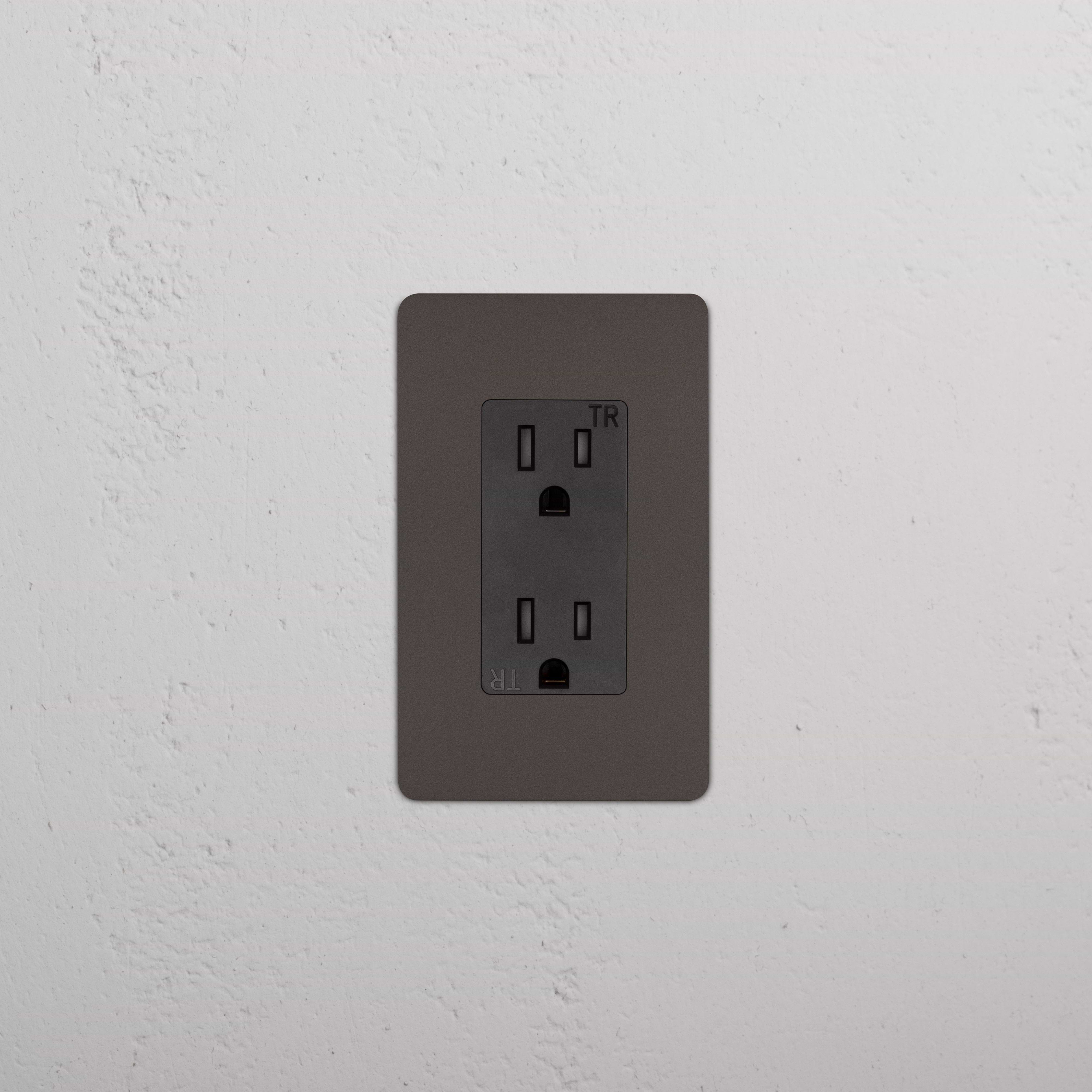 Kew 1G 15A electrical outlet in bronze black finish, single socket, mounted on a white wall.