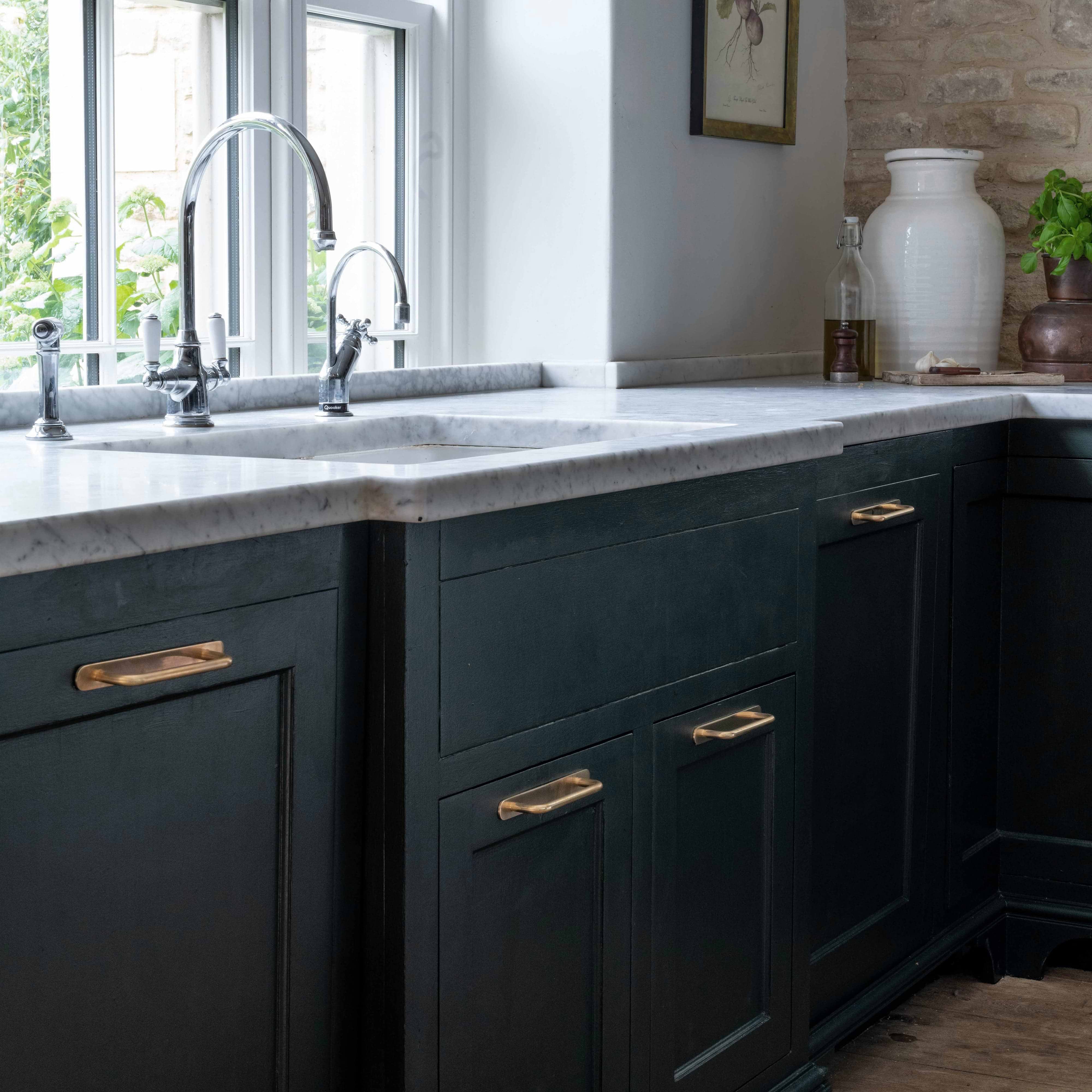 Close-up of Kilburn Furniture Handle Small in antique brass mounted on a dark green cabinet drawer.