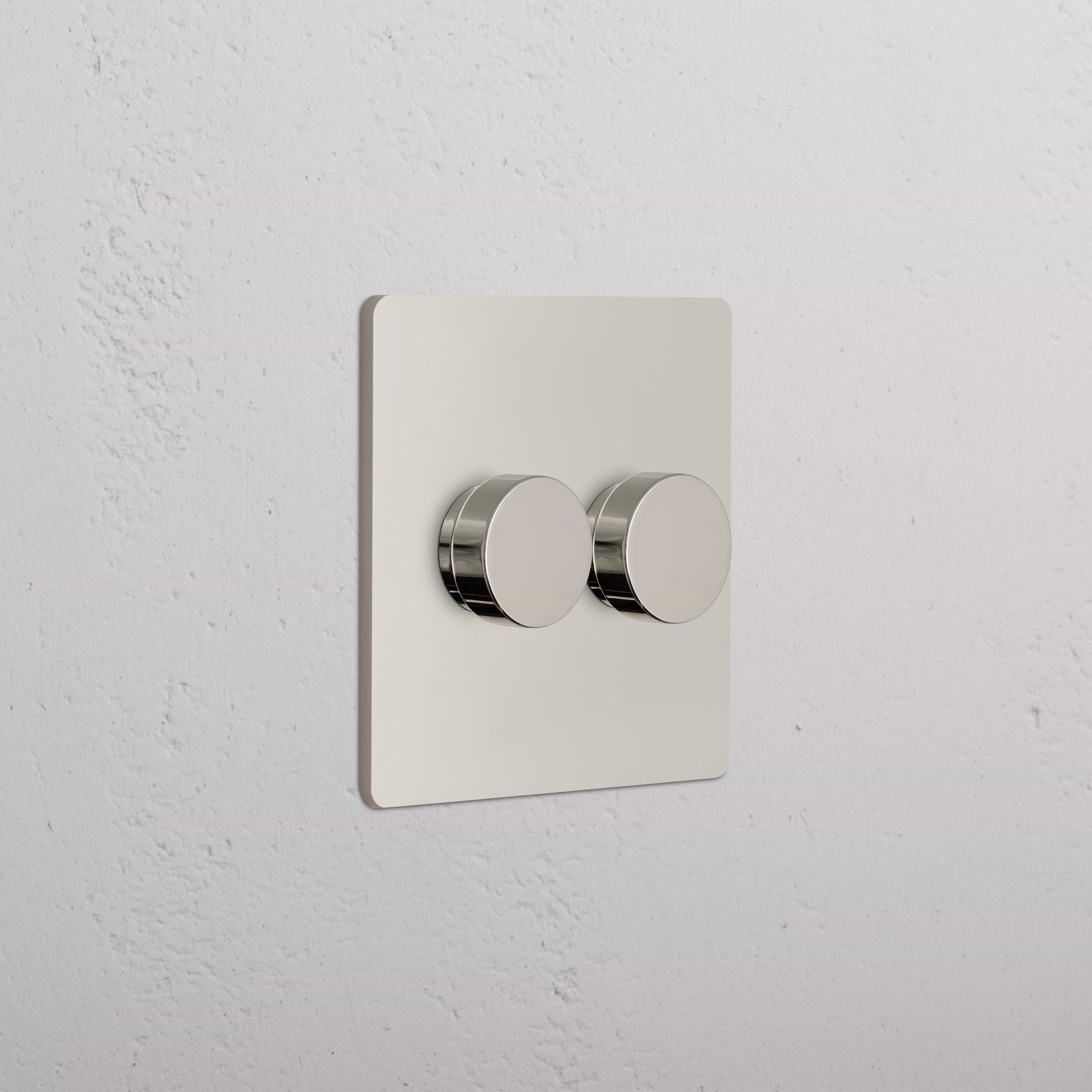 Grove 2G Dimmer Switch in polished nickel with two round knobs, shown mounted on a white wall.