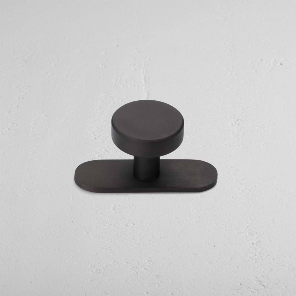 Kilburn Furniture Knob in bronze finish, featuring a circular handle and rounded rectangular base.