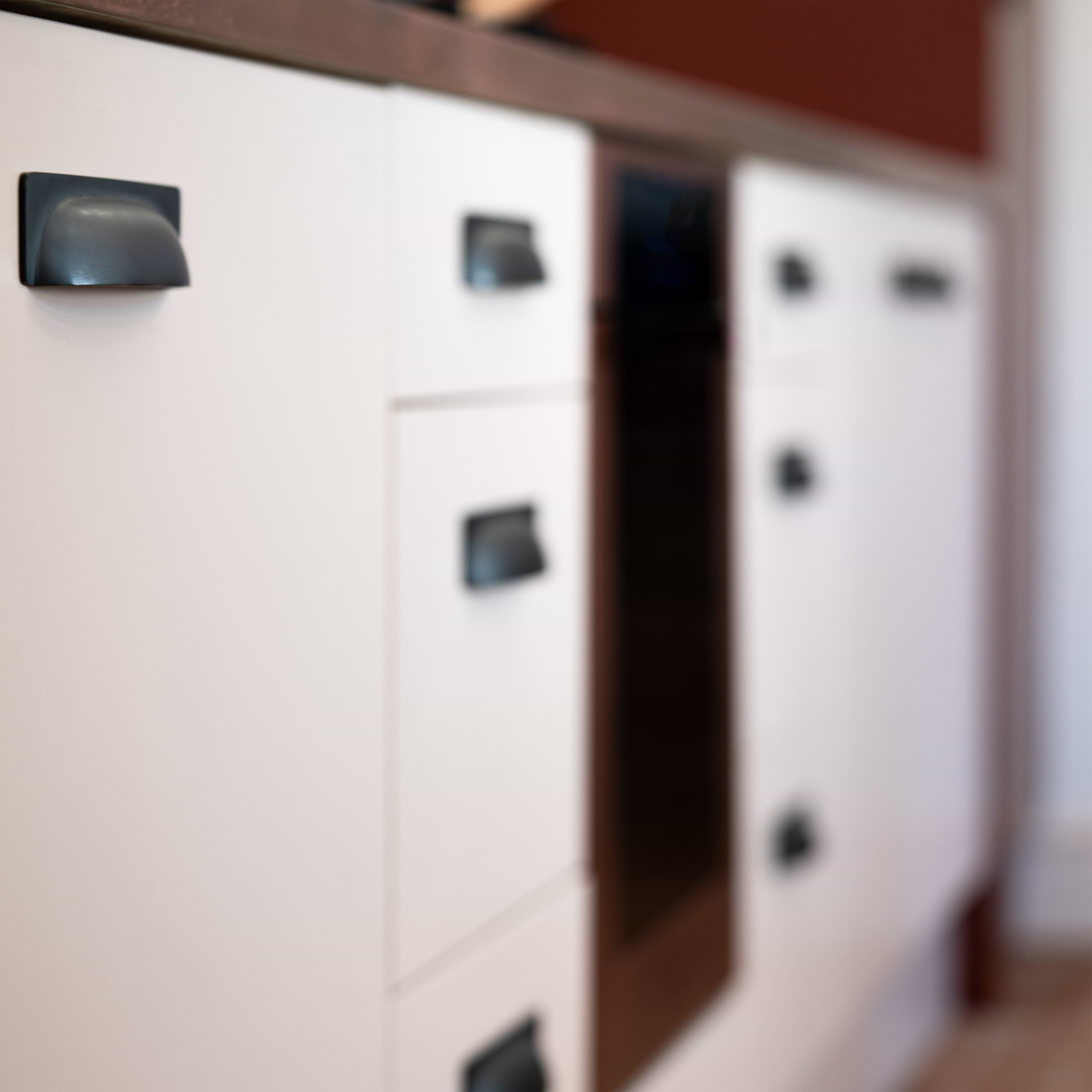 Close-up of kitchen drawer featuring the Elm Cup Handle Small in bronze on a white cabinet front.