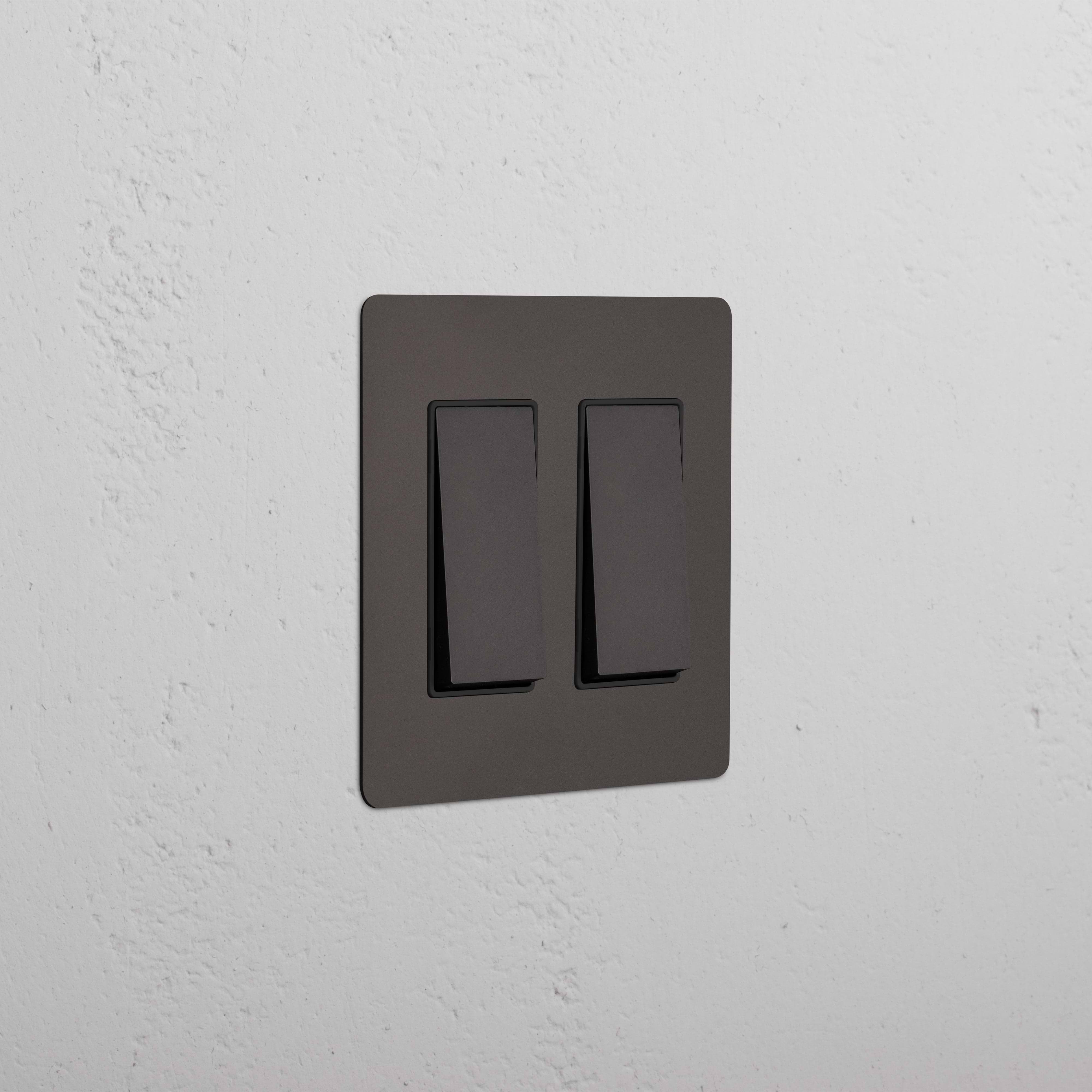 Kew 2G Rocker Switch in Bronze Black finish, both switches off, shown on a white textured wall.
