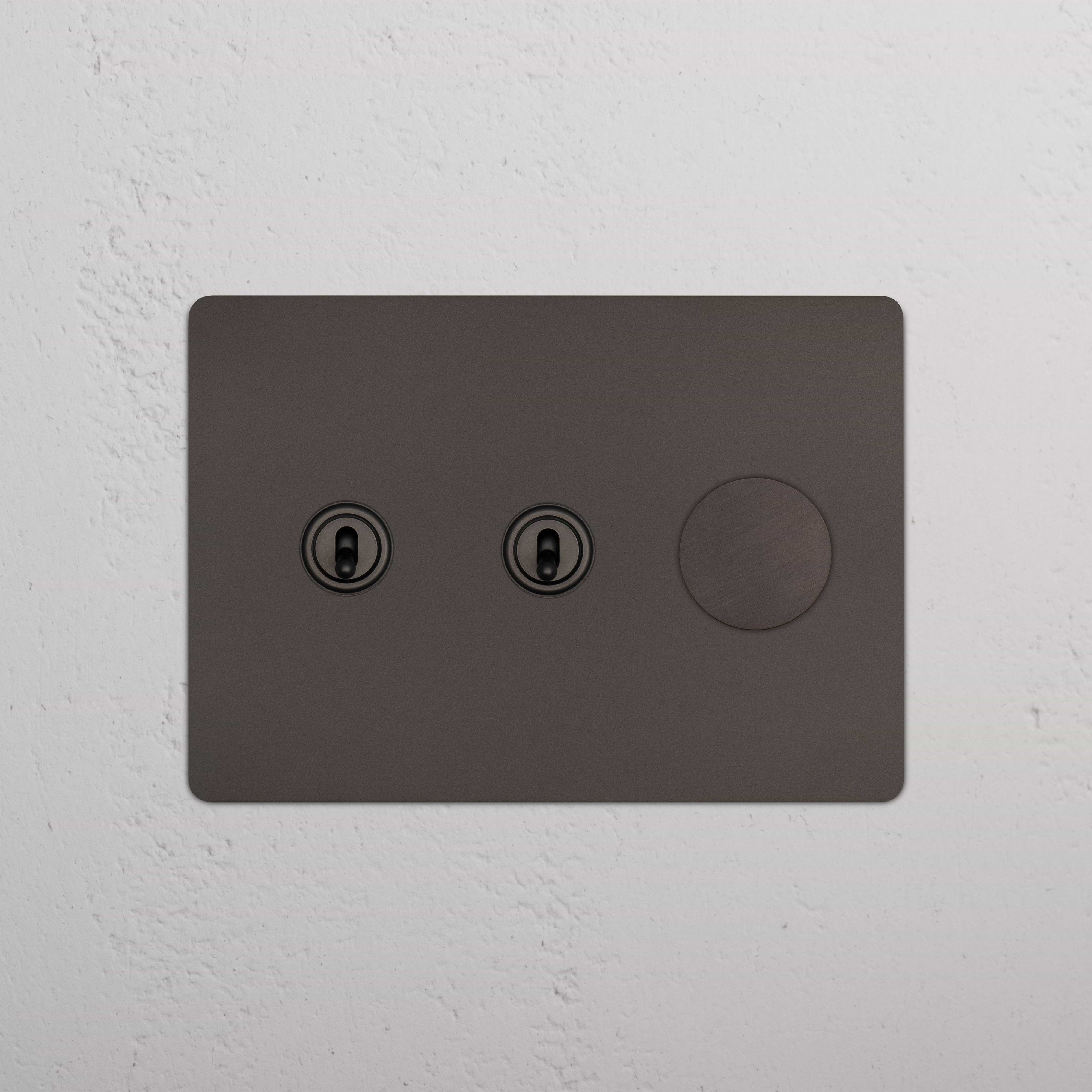 Bronze Kew 3G 2x Toggle & Dimmer Switch with two toggle switches and one dimmer knob on a wall.
