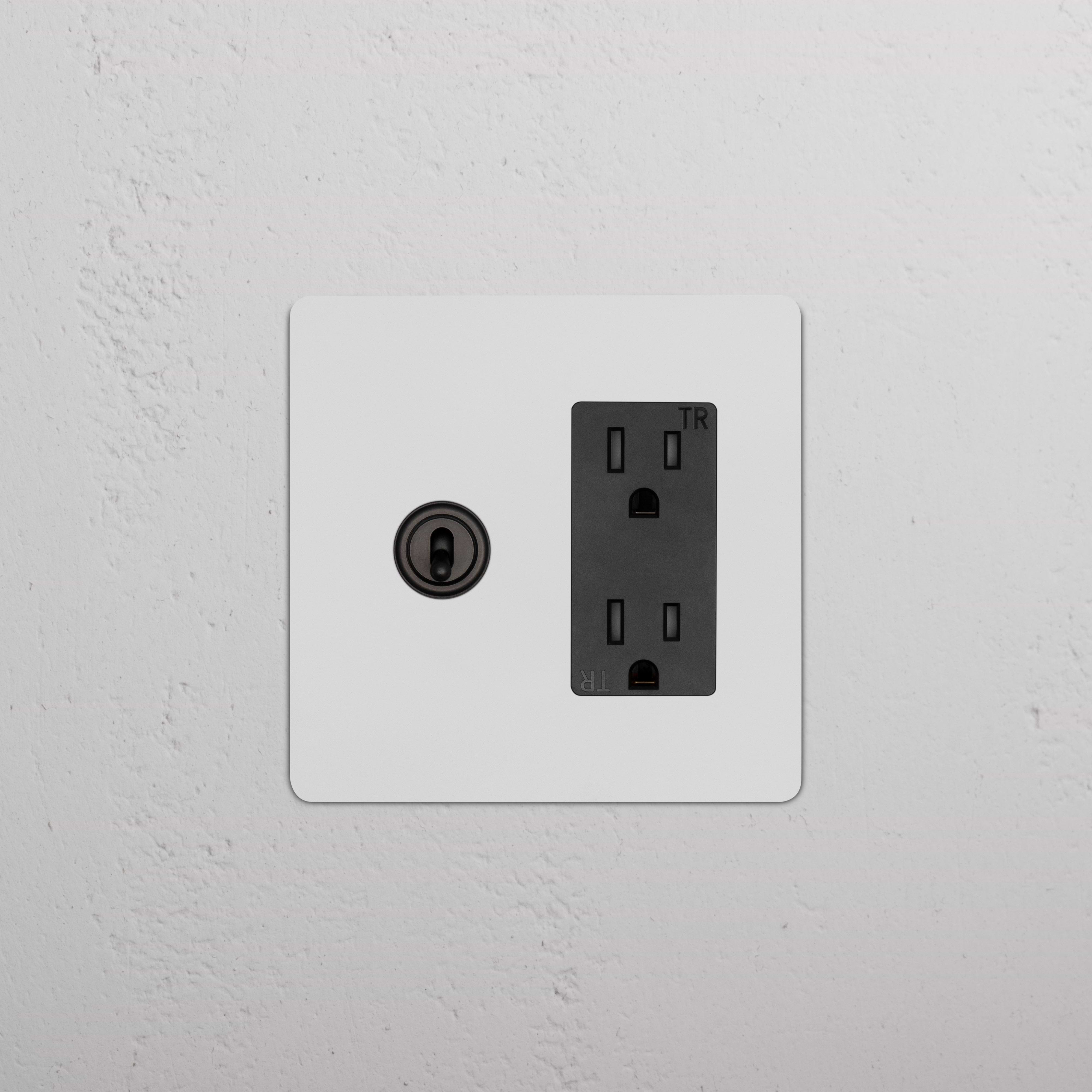 Kew 2G Toggle Switch & Outlet in Paintable Bronze Black finish, mounted on a white wall.