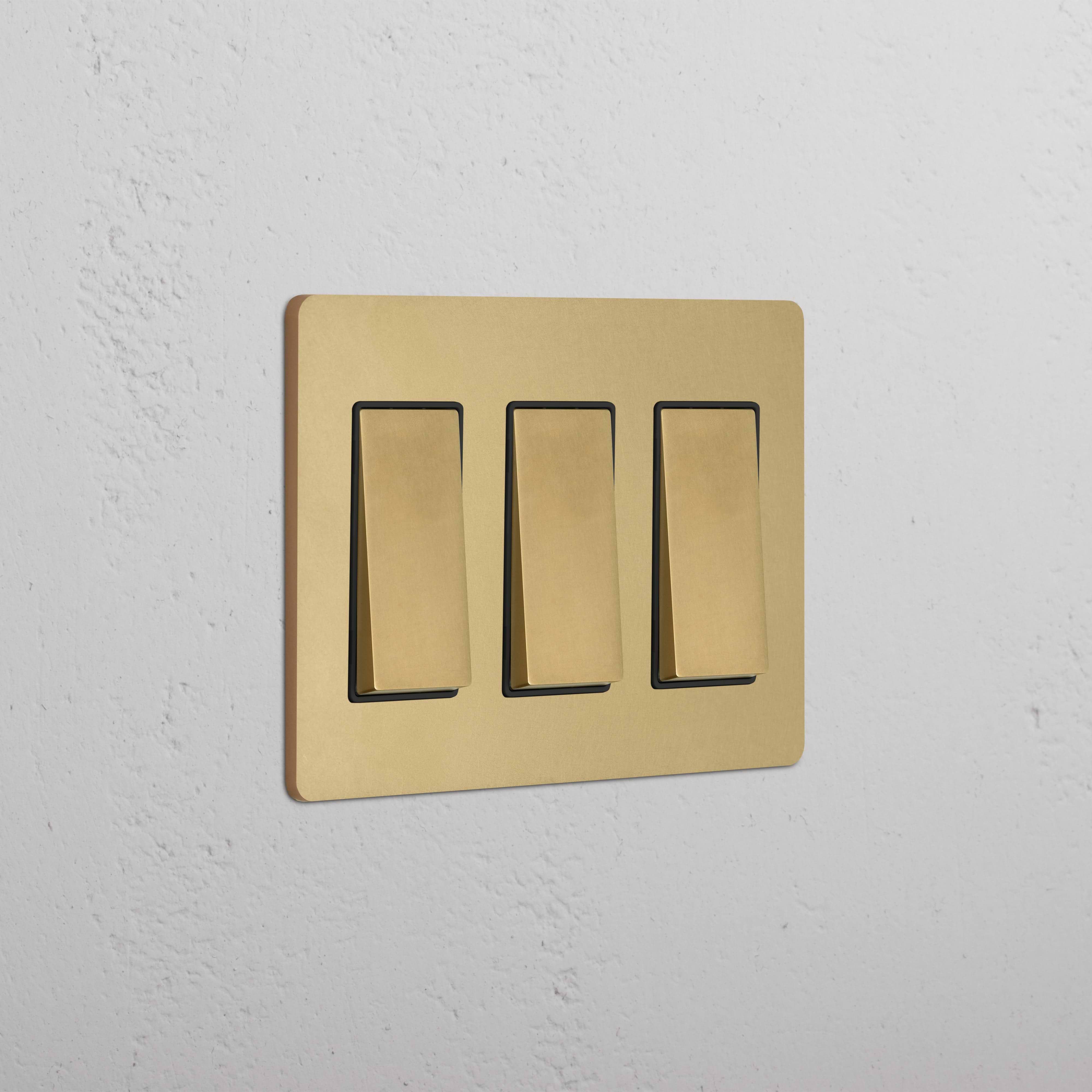 Grove 3G Rocker Switch in Antique Brass Black finish, shown with three switches on a white wall.