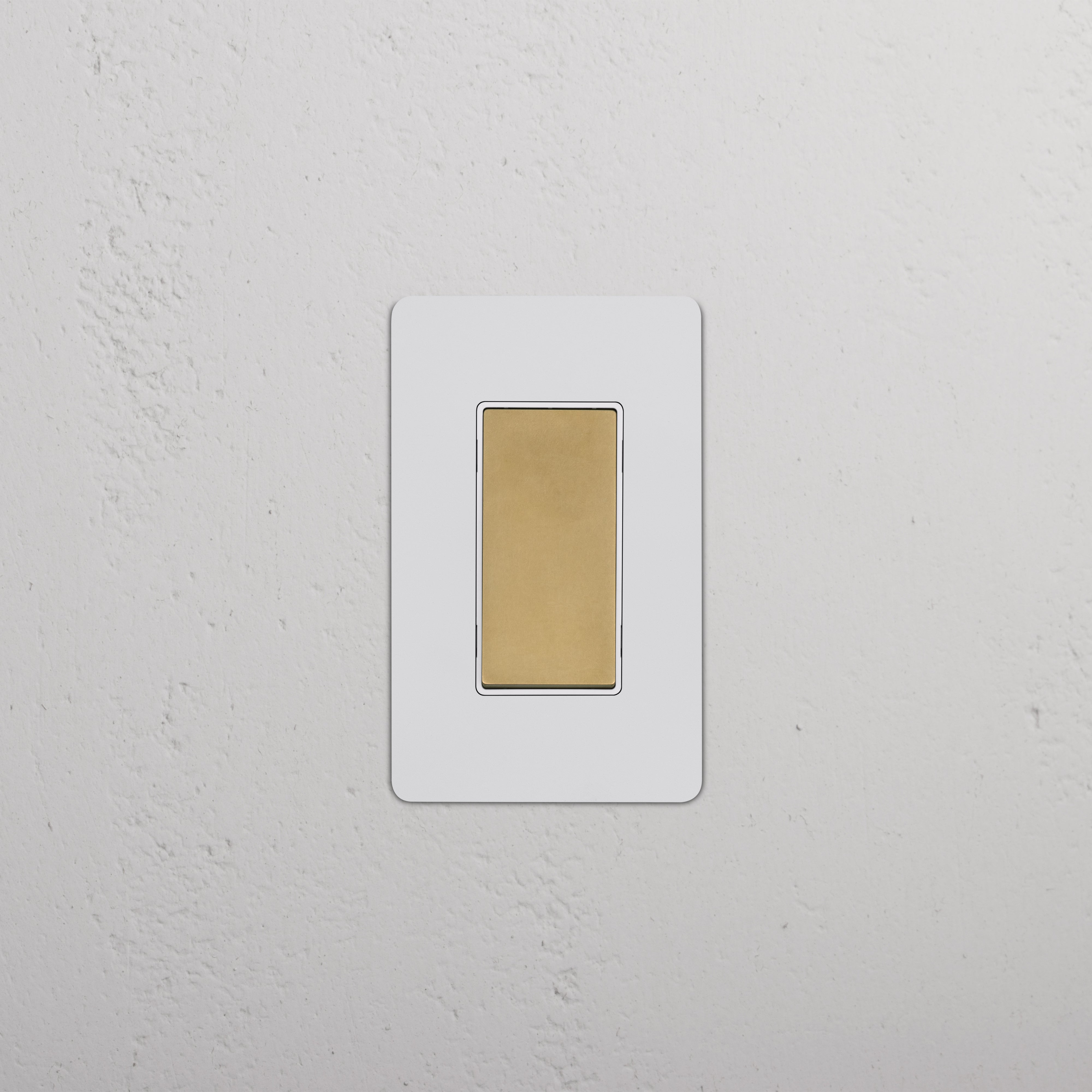 Kew 1G Smart Retractive Rocker Switch in paintable antique brass white, mounted on a textured white wall.