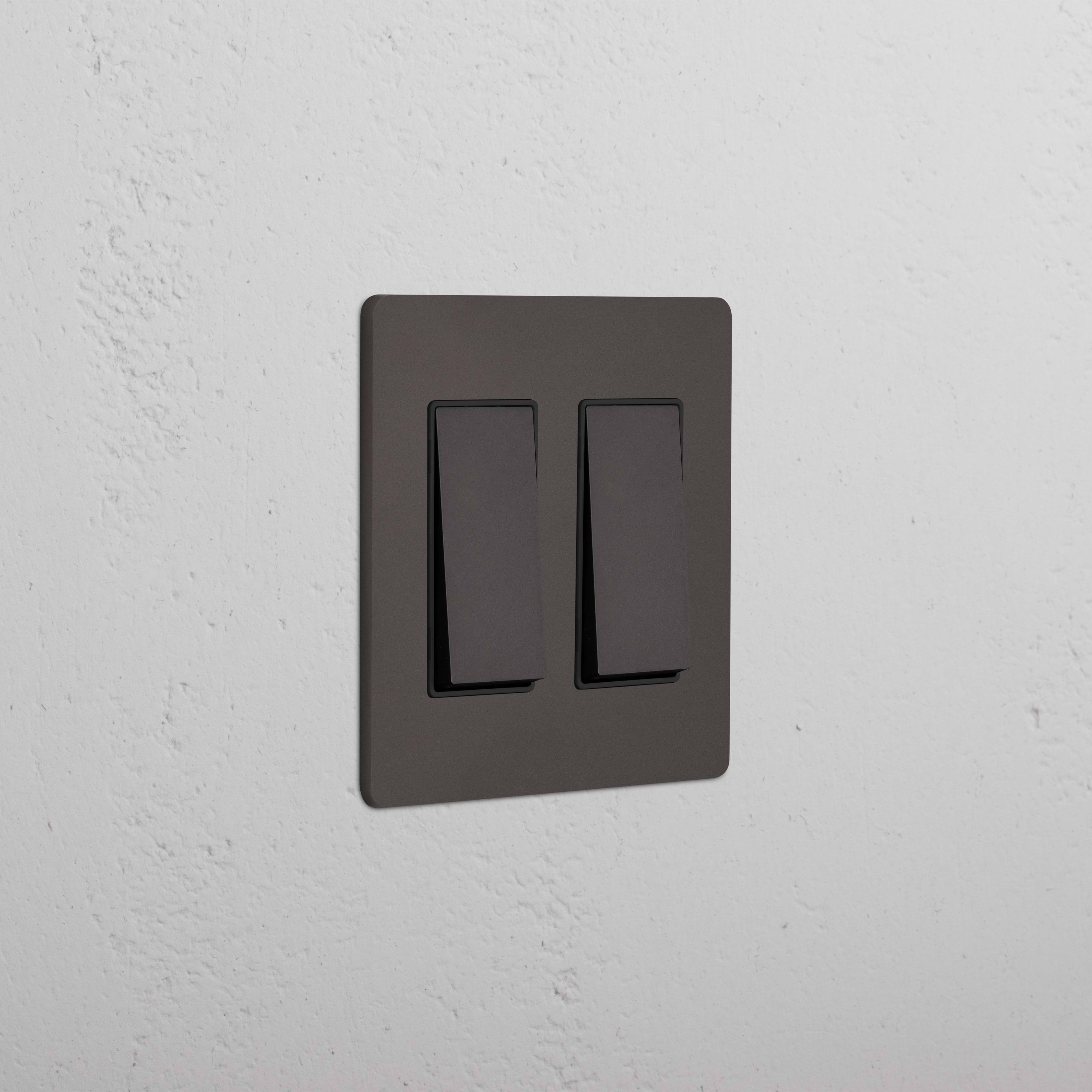 Grove 2G Rocker Switch in Bronze Black, shown mounted on a white wall with both switches off.
