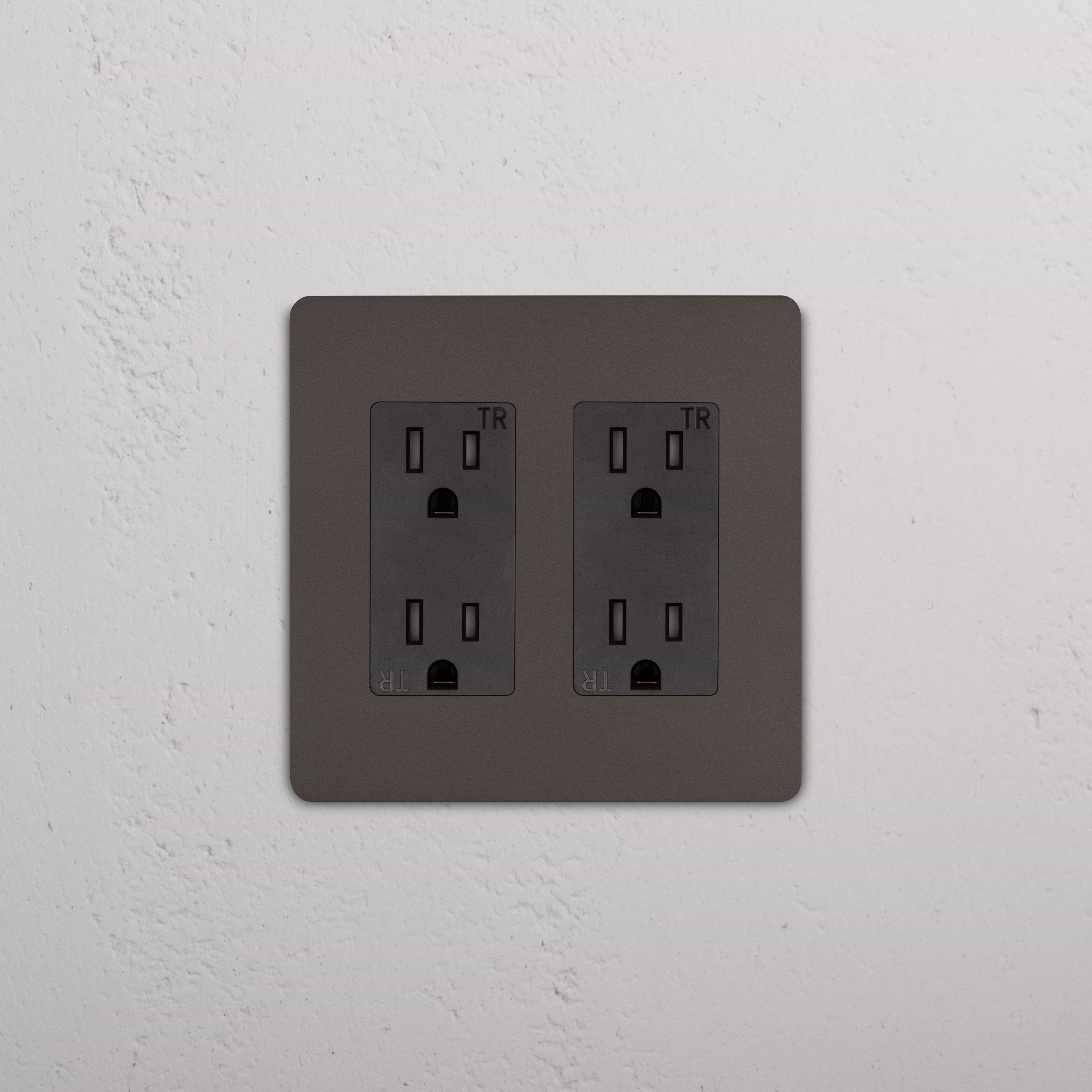 Grove 2G Outlet in Bronze Black, featuring two standard power outlets on a white textured wall.