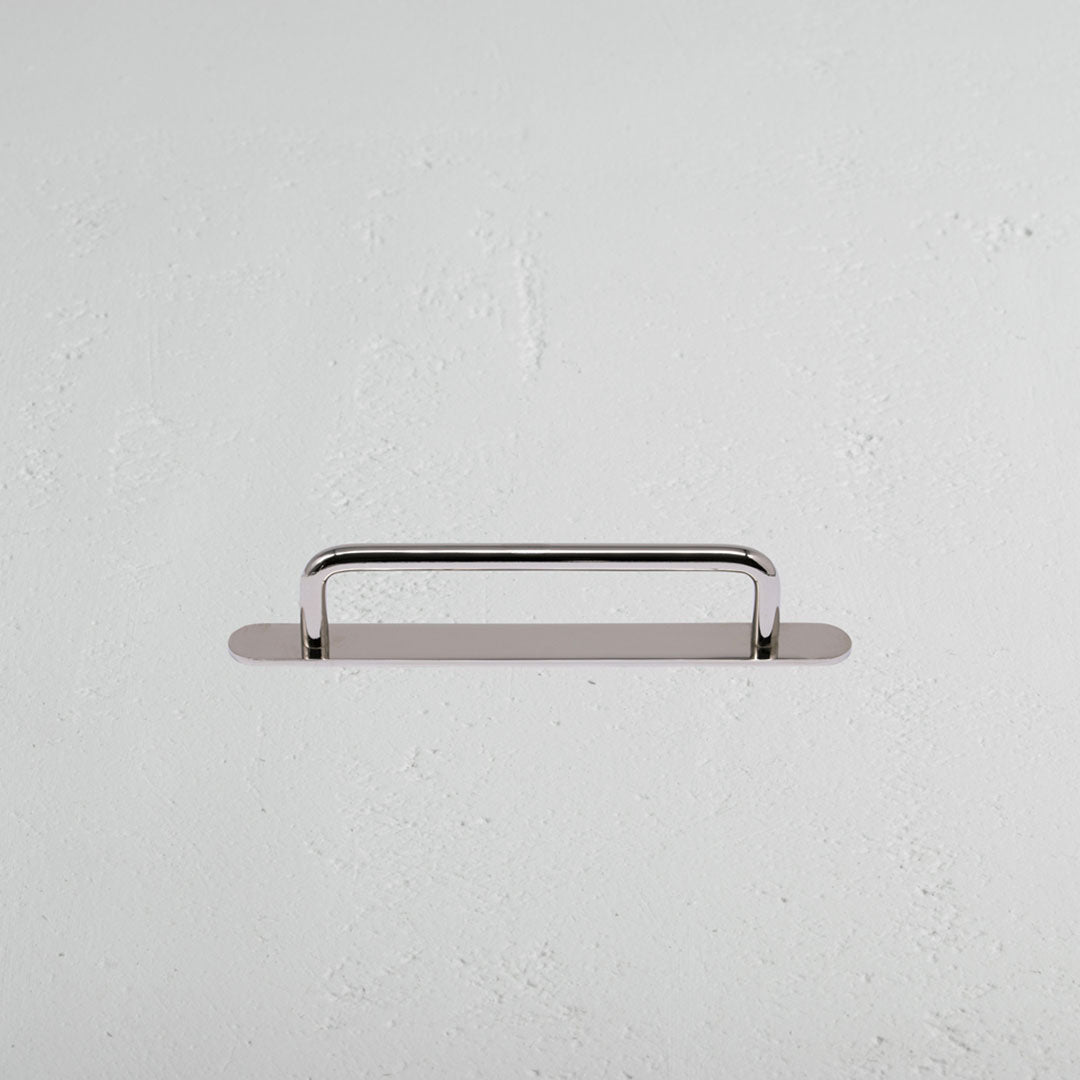 Kilburn Furniture Handle Small in polished nickel, mounted horizontally on a white textured wall.