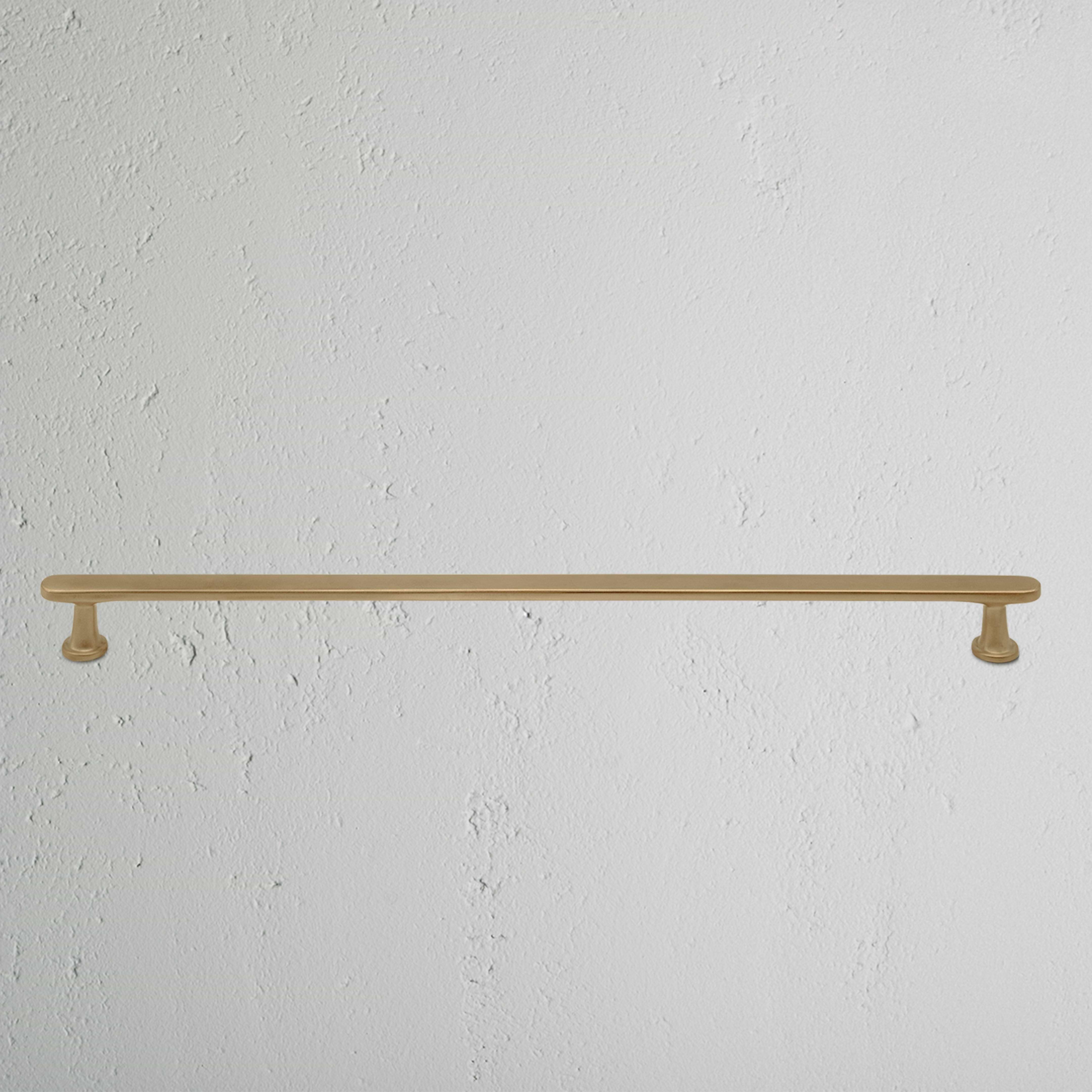Large antique brass Milliner furniture handle with a straight, simple design mounted on a white surface.