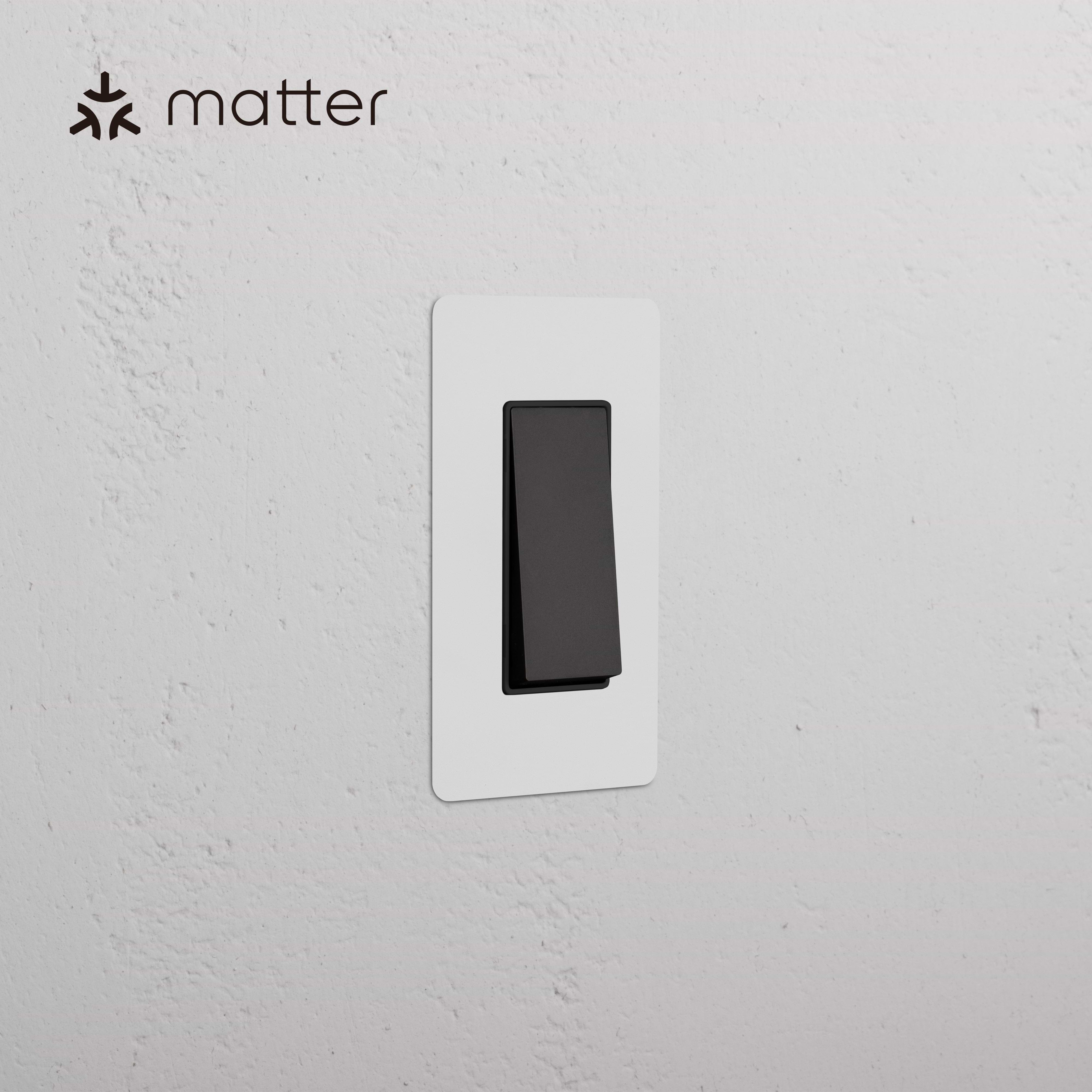 Kew 1G Smart Retractive Rocker Switch in Paintable Bronze Black, shown with a white cover plate on a white wall.