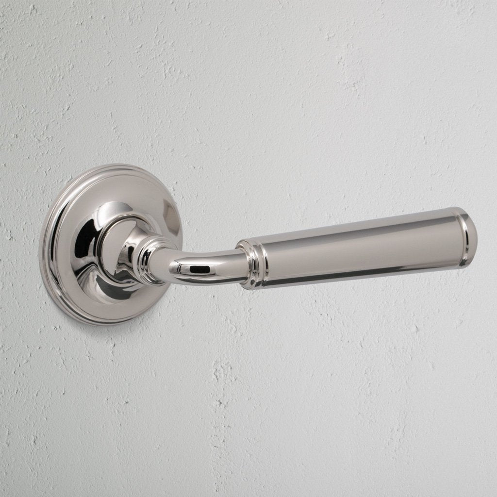 Close-up of Digby Passage Door Handle Unsprung in polished nickel finish, mounted on a white wall.