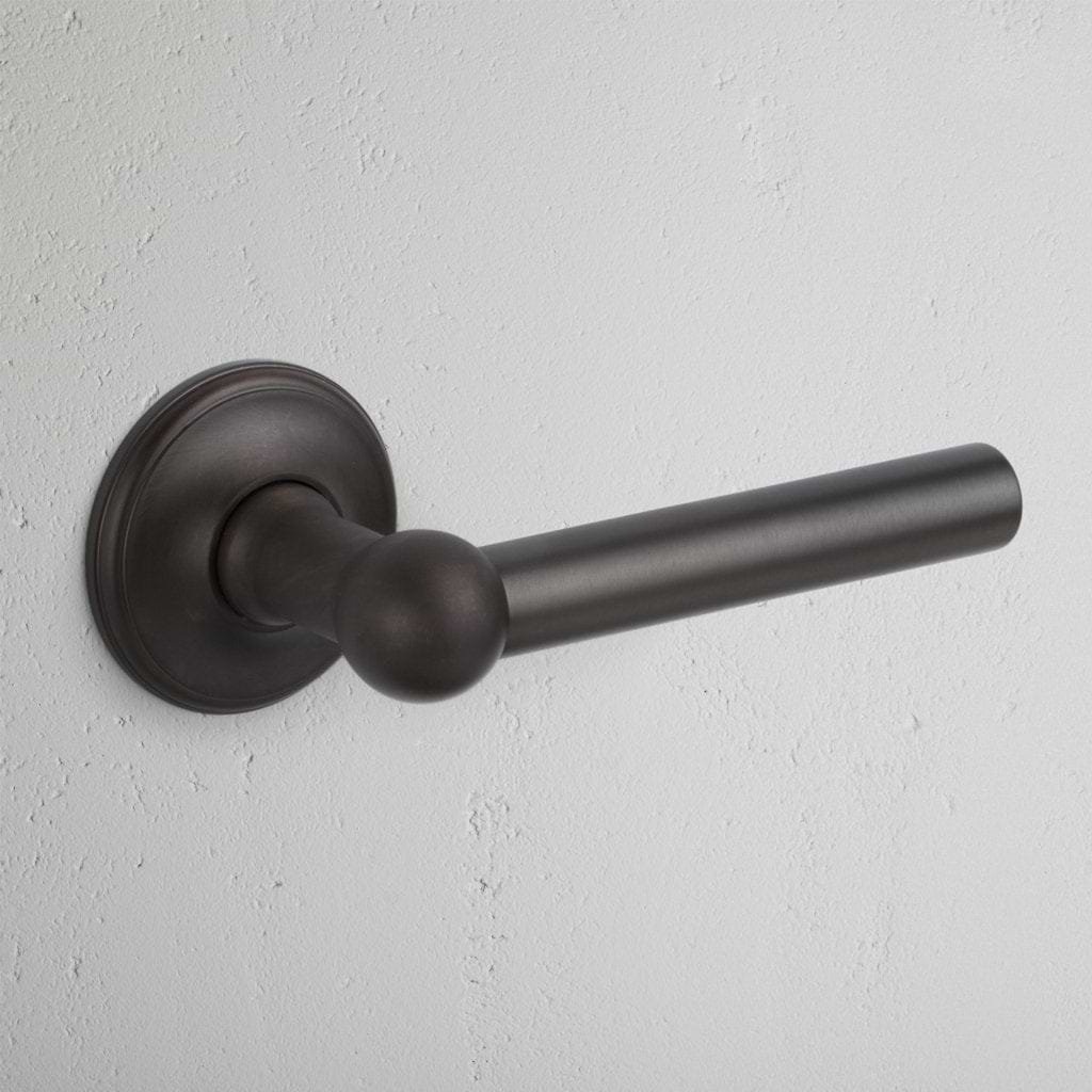 Harper Dummy Door Handle Set in bronze finish, shown mounted on a light textured wall.